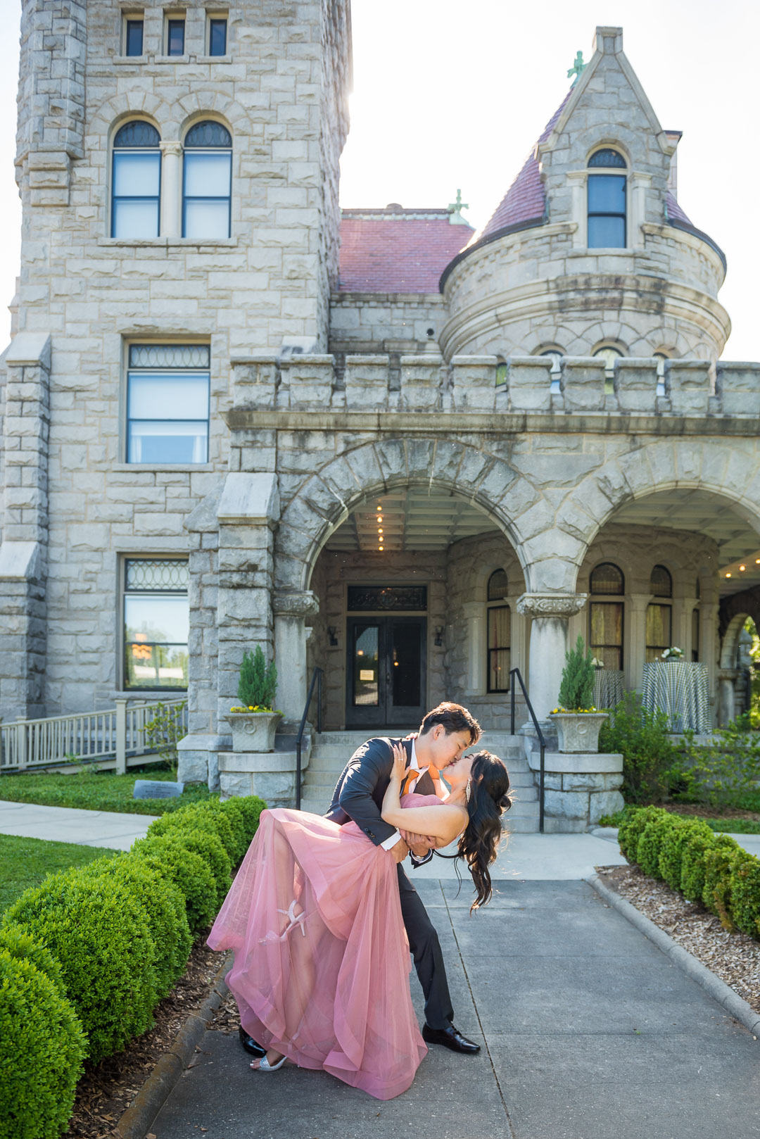Man dipping his partner in a pink gown in front of the stone castle facade of Rhodes Hall in Atlanta