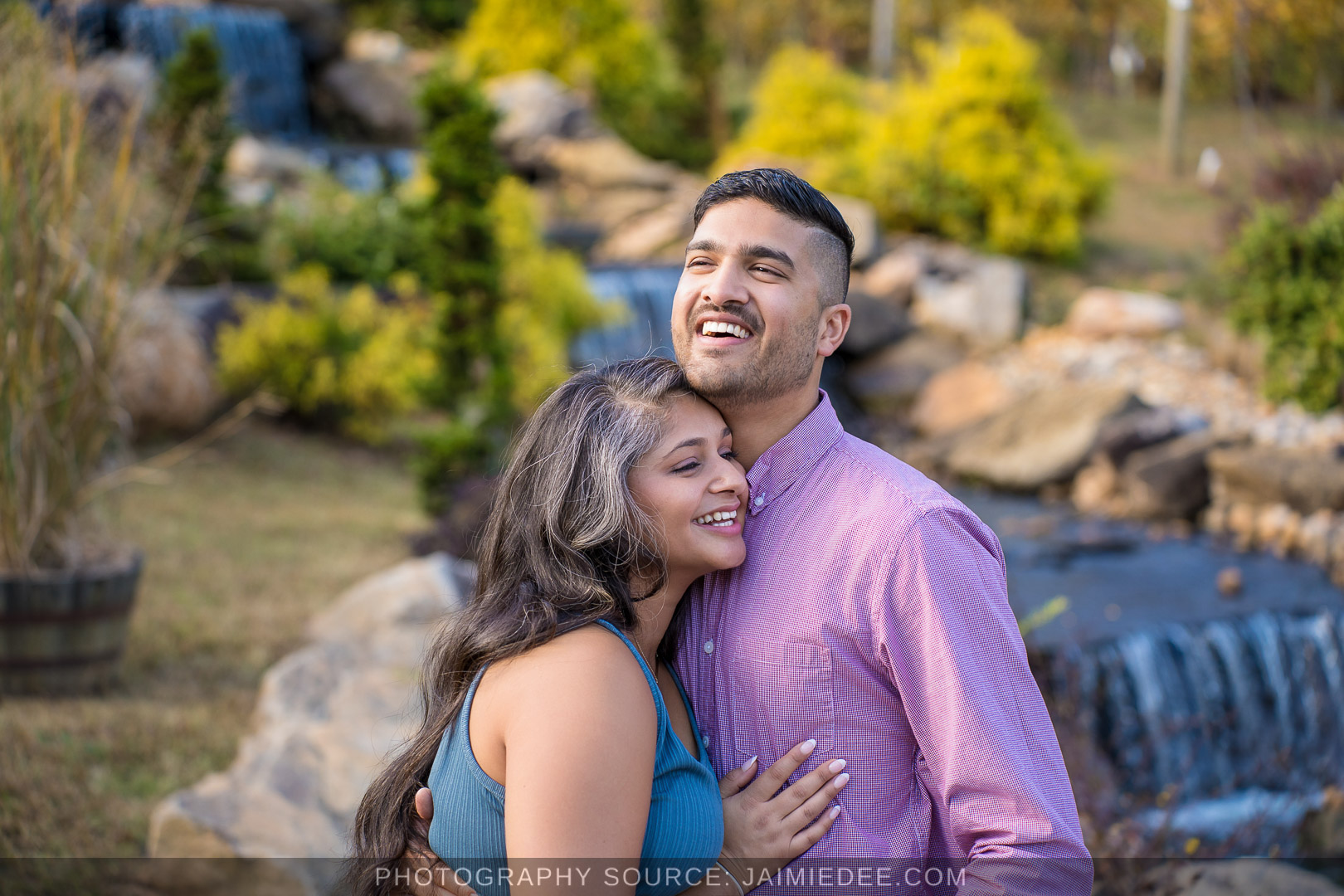 Engaged couple laughing together beside the waterfall and rock garden at Big Door Vineyards