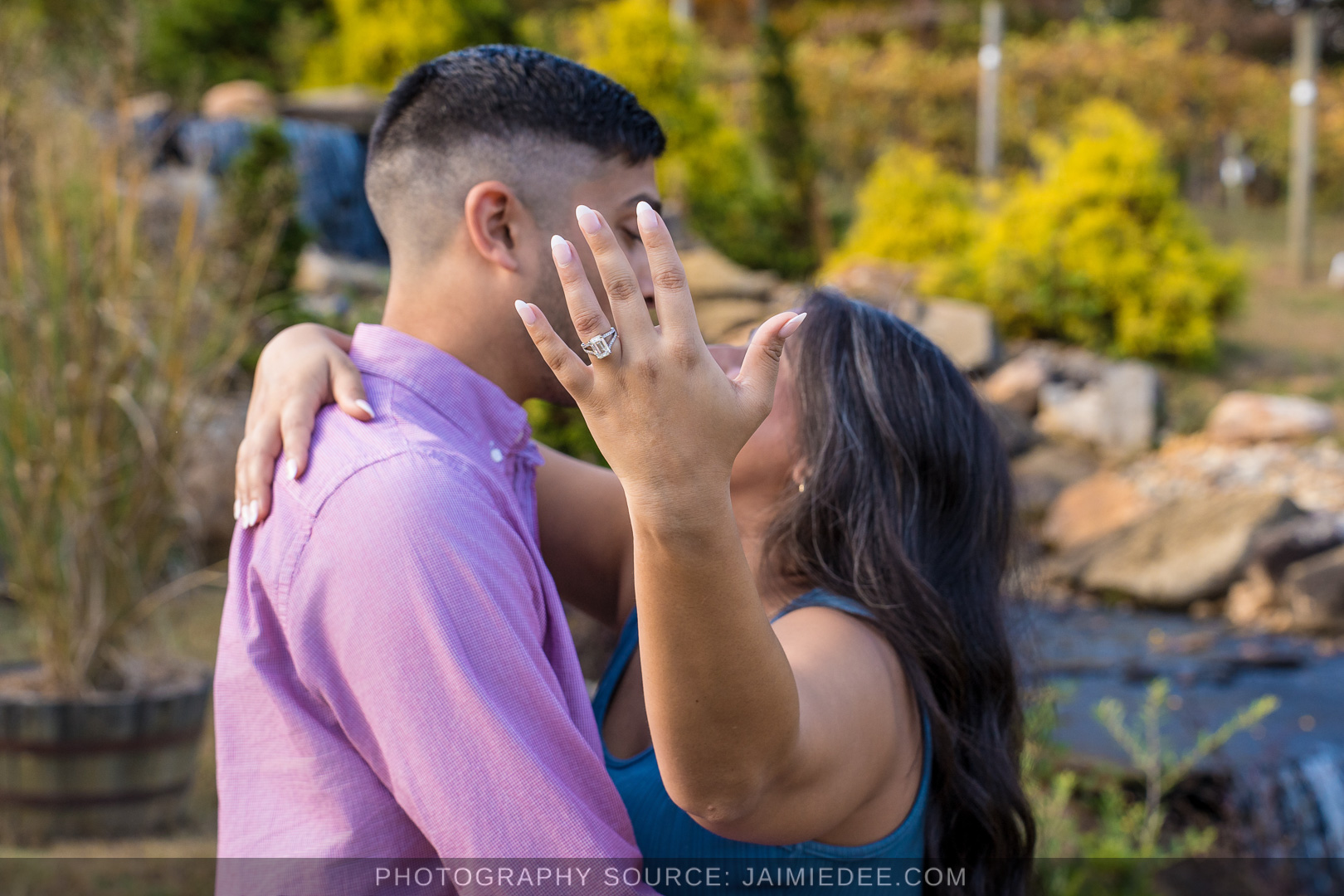 Woman admiring her engagement ring with her fiance by the waterfall at Big Door Vineyards
