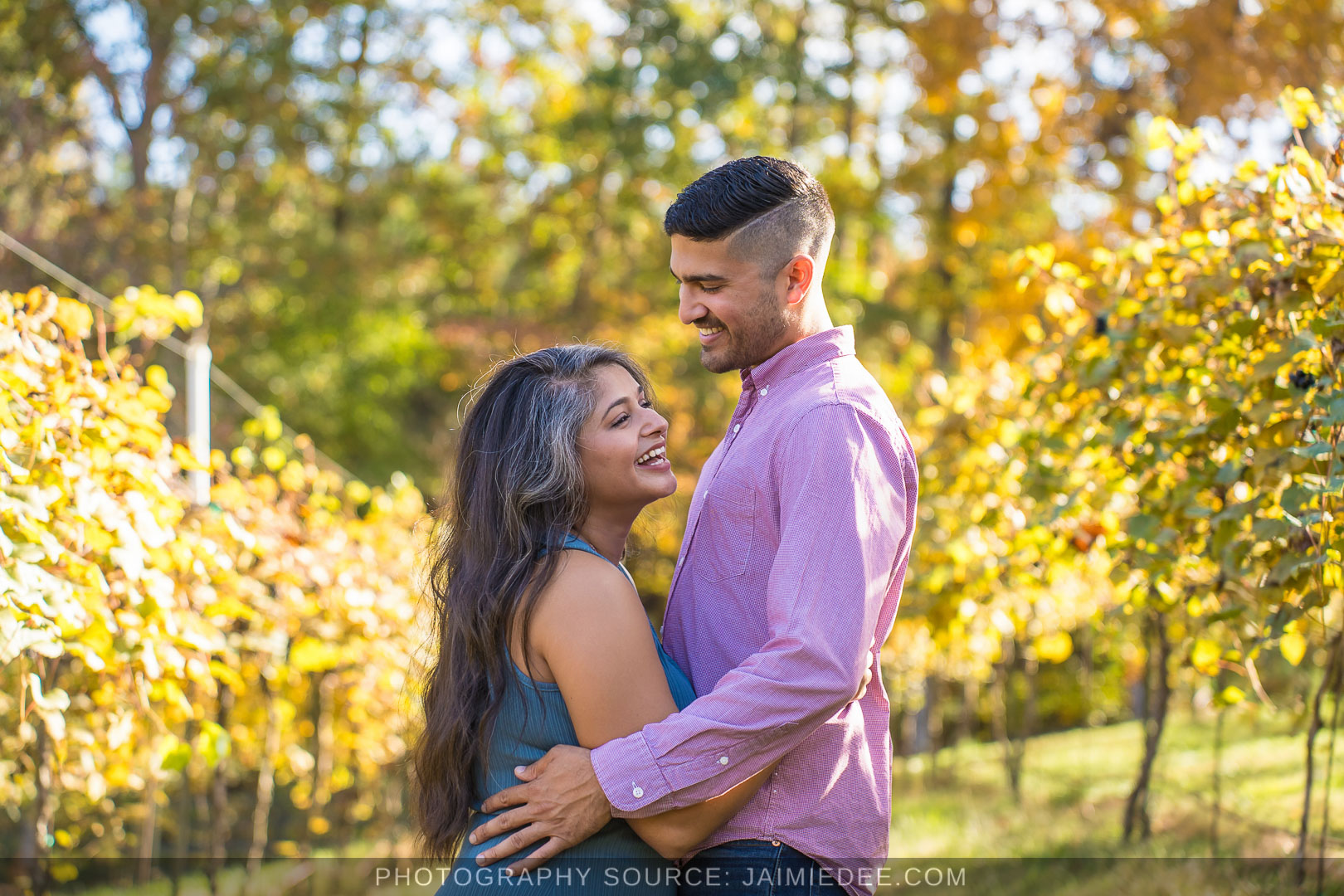 Couple hugging and laughing in the fall vineyard at Big Door Vineyards