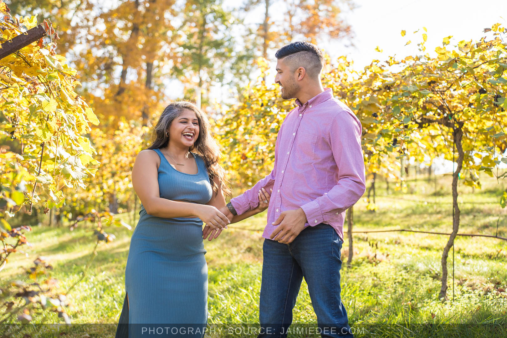 Couple laughing and holding hands in the vineyard rows at Big Door Vineyards