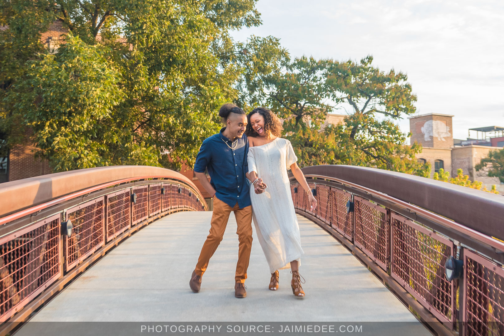 Couple walking hand in hand across the red footbridge at Westside Provisions District