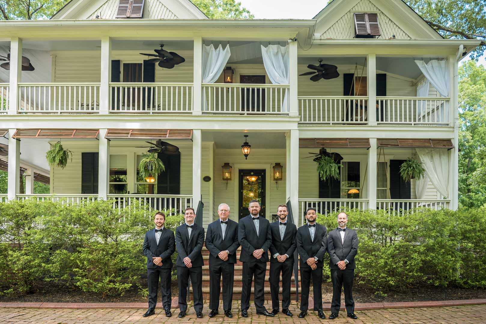 Groom and groomsmen standing in front of historic Wheeler House