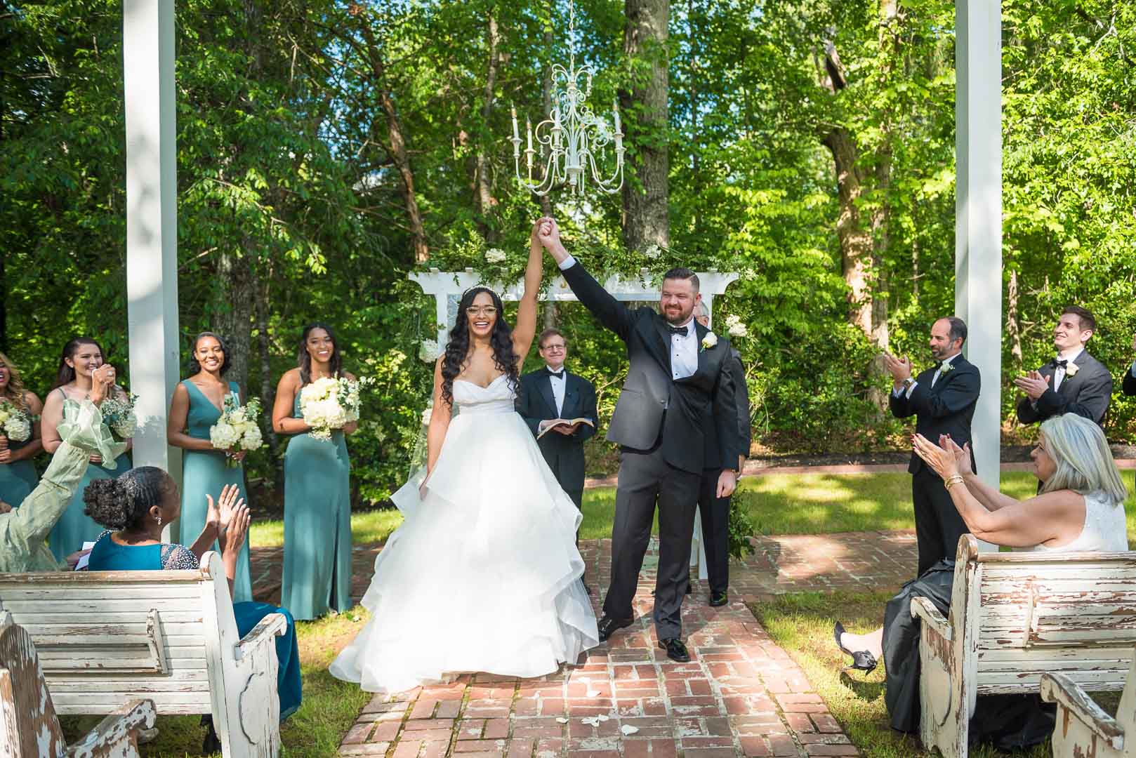 Newlyweds celebrating at the outdoor ceremony space at The Wheeler House as guests cheer