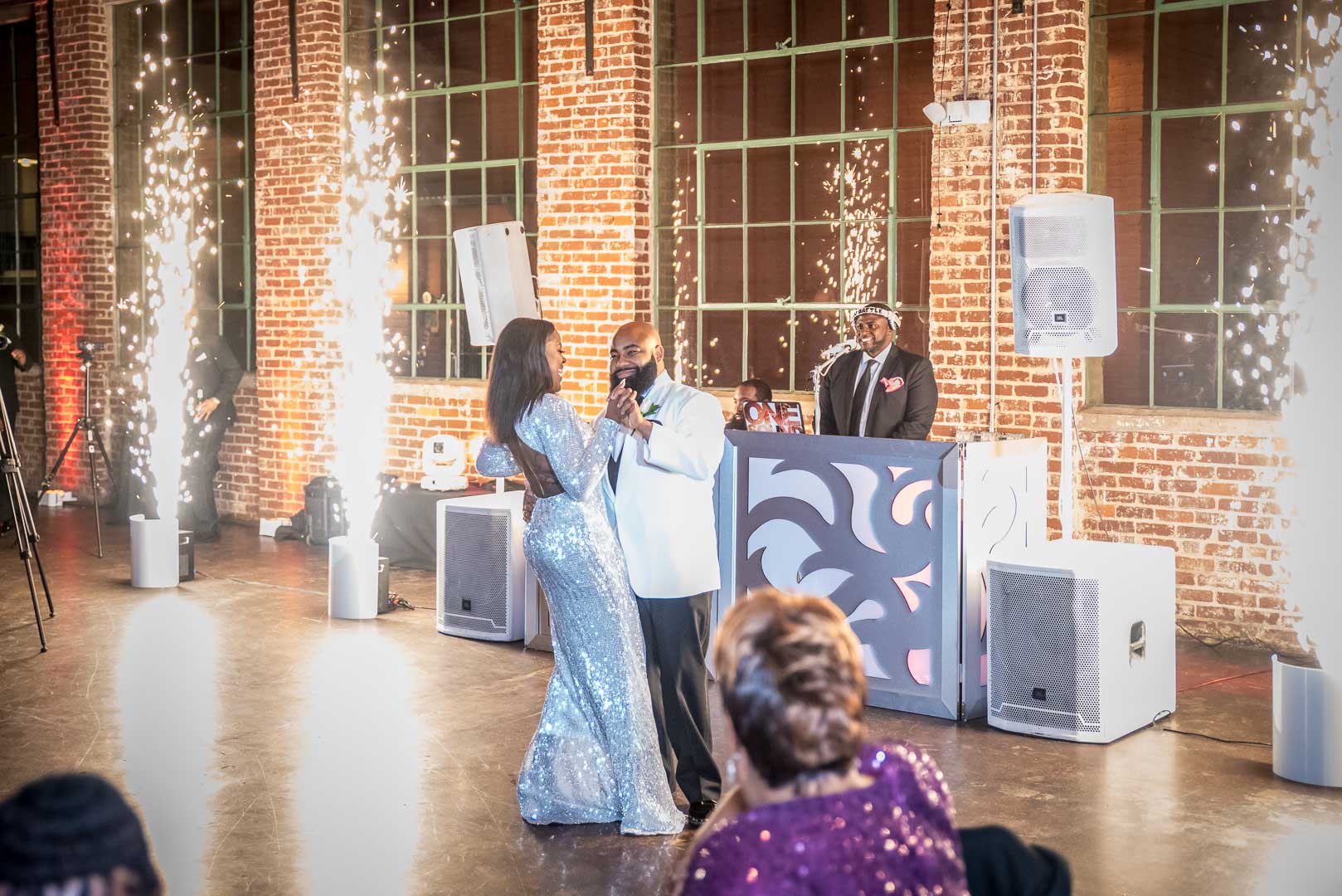 Couple sharing their first dance between cold spark fountains at an industrial reception venue
