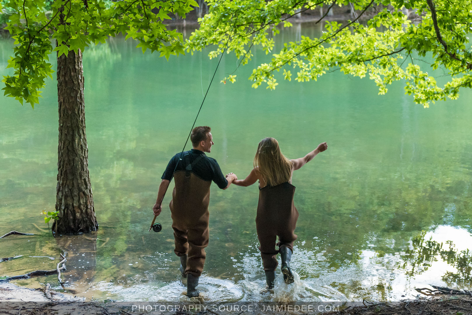 Couple wading hand in hand along the wooded shoreline of Lake Lanier