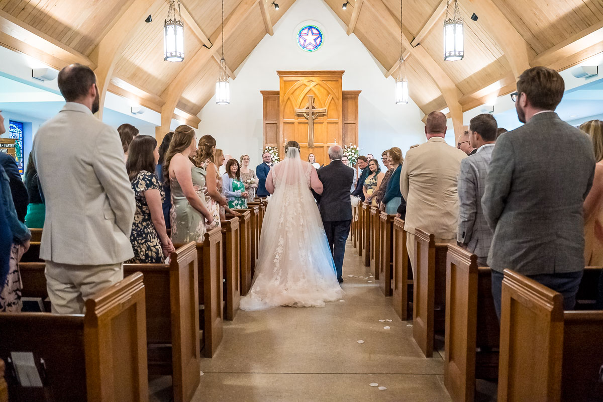 Bride walking down the aisle towards the groom during wedding ceremony at The Episcopal Church of the Epiphany