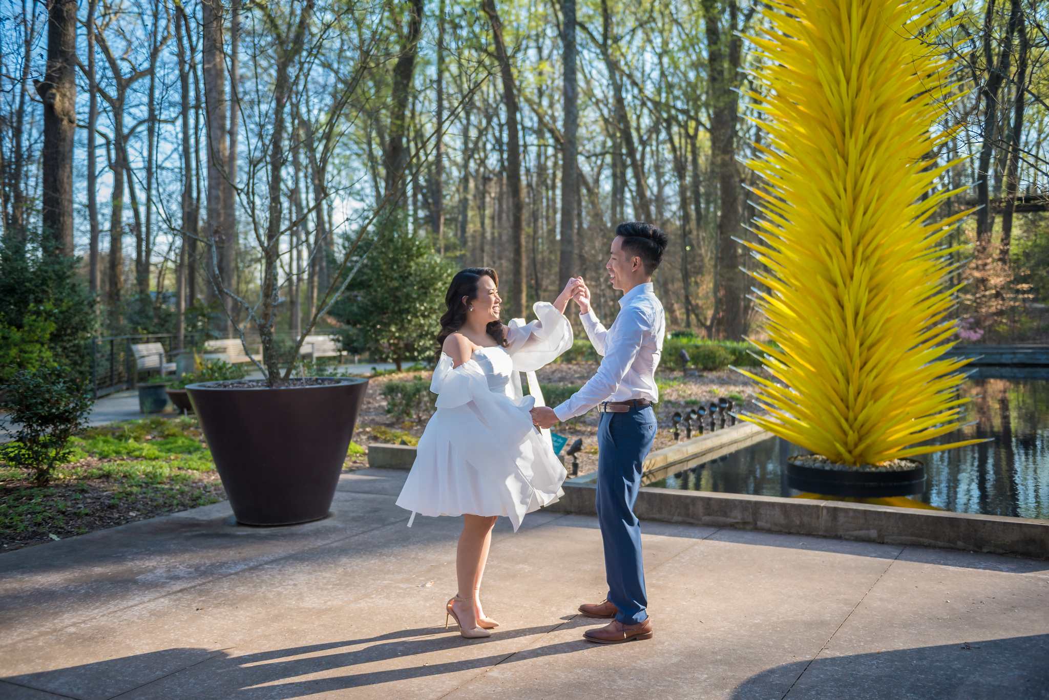 Couple twirling beside the tall yellow glass sculpture at the Atlanta Botanical Garden