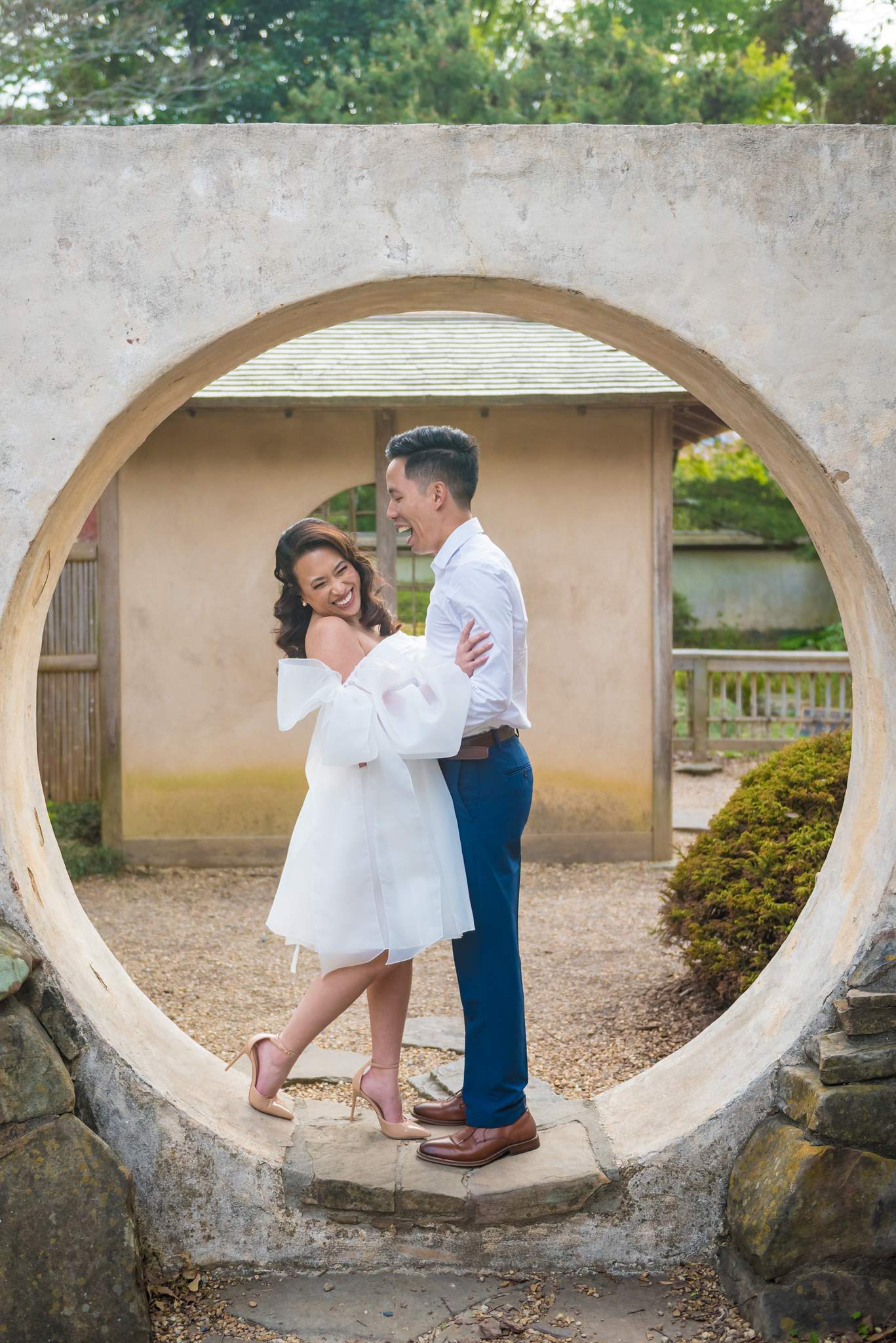 Vertical photo of a couple standing inside the round moon gate in the Japanese Garden
