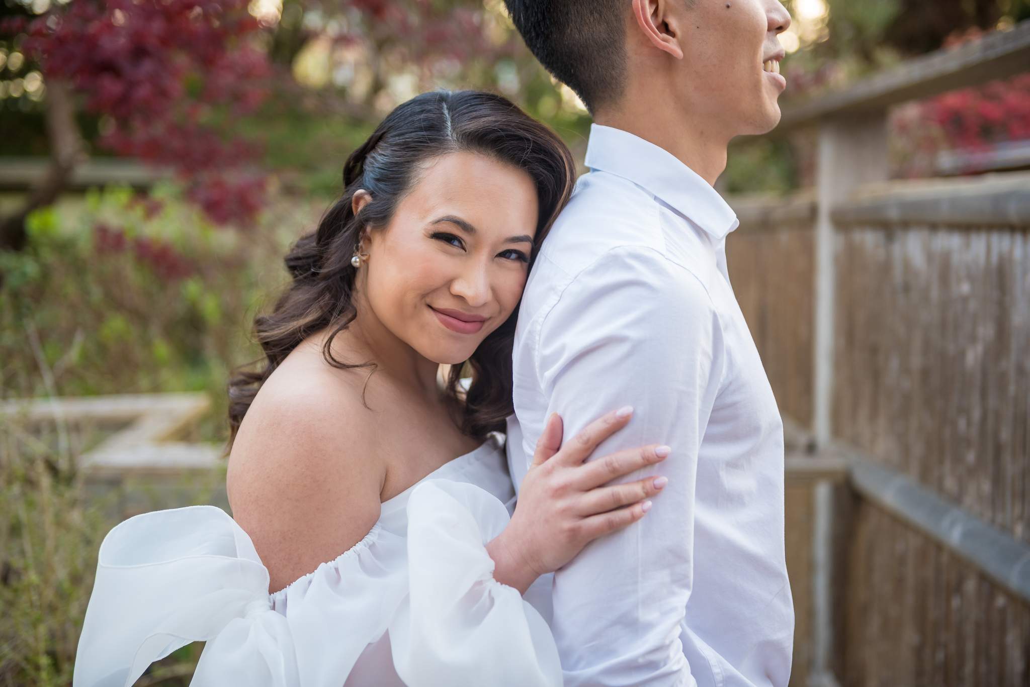 Bride-to-be resting her head on her partner's chest in the Japanese Garden