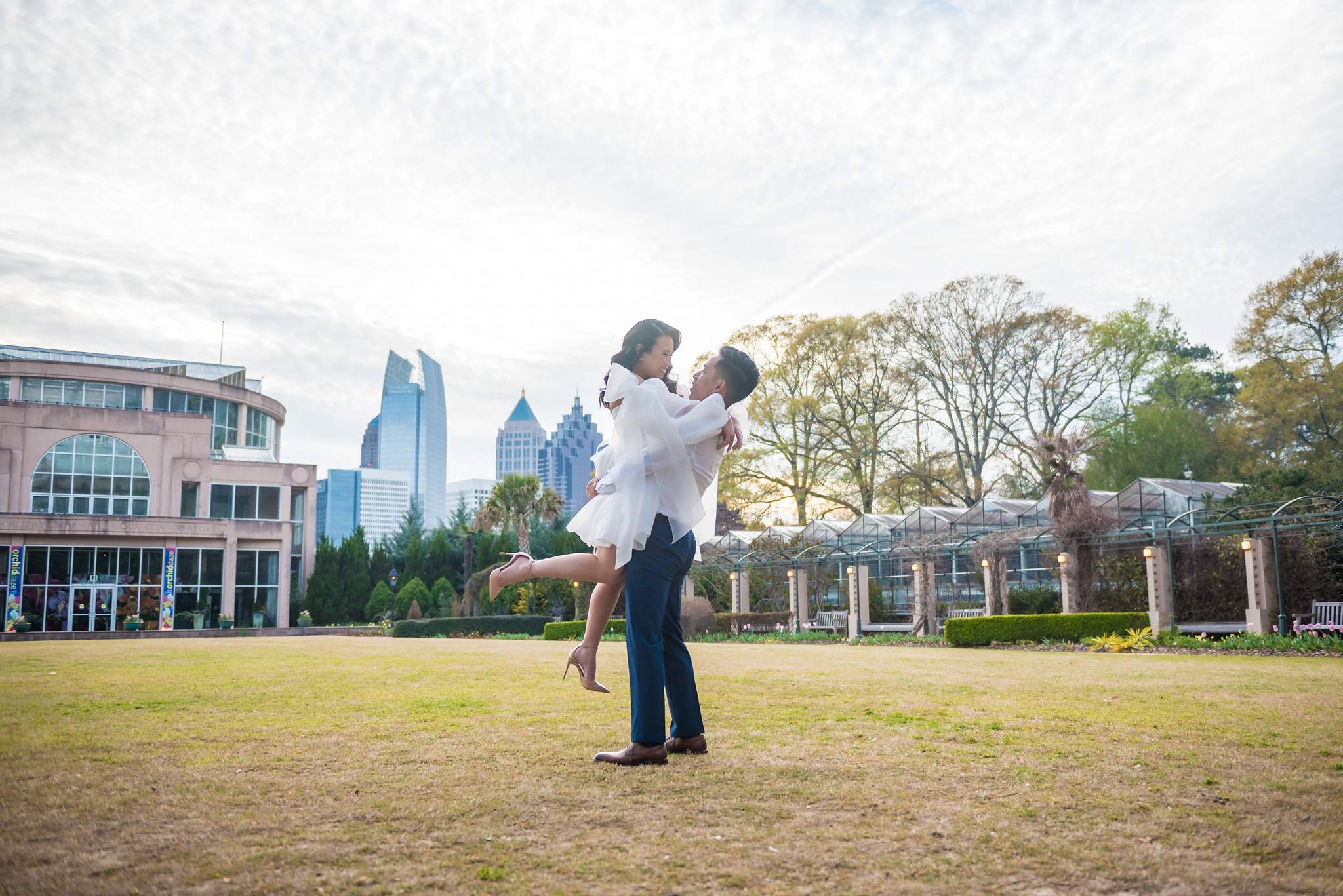 Partner lifting her into the air on the lawn with the Midtown Atlanta skyline