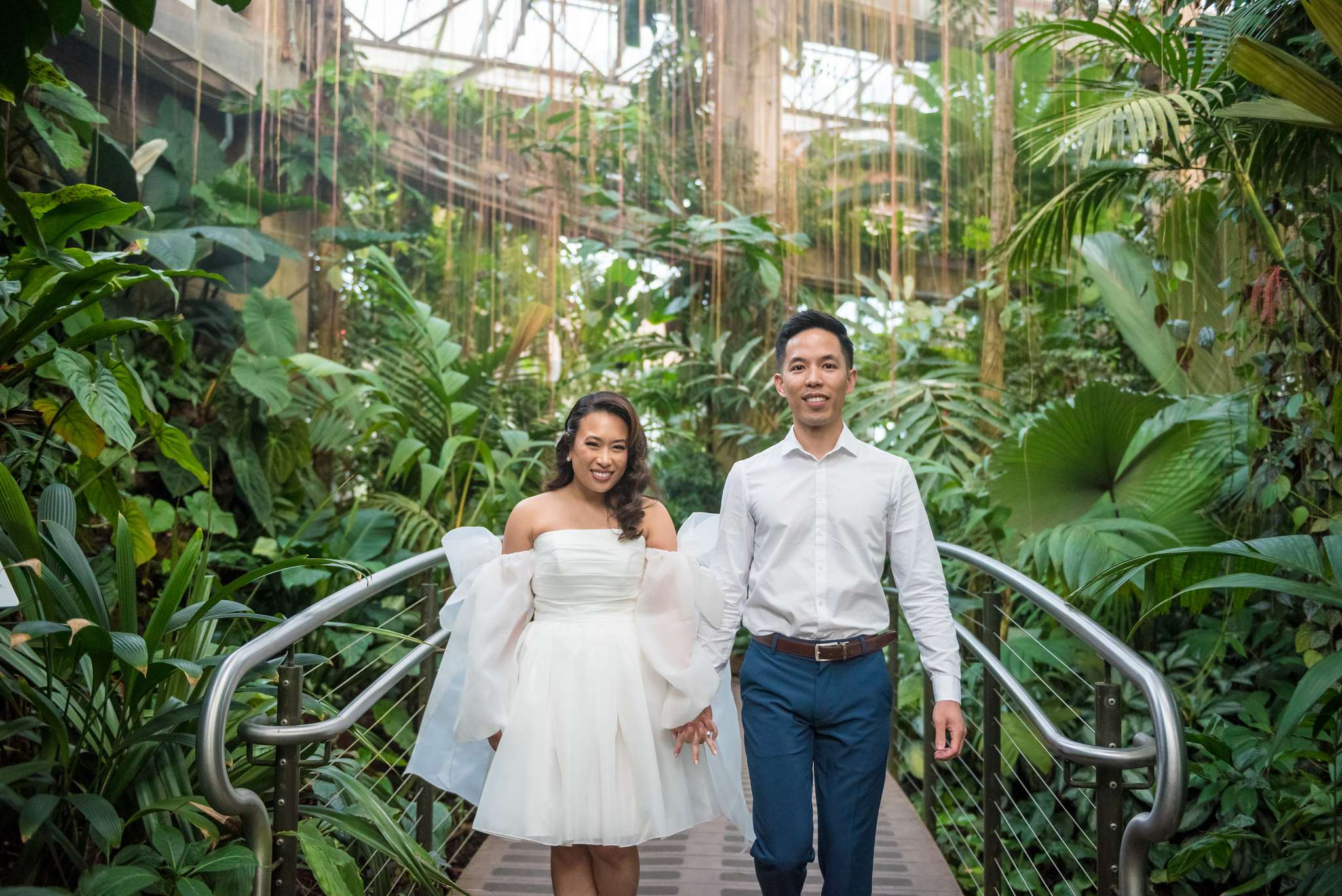 Couple walking hand in hand across the conservatory canopy bridge
