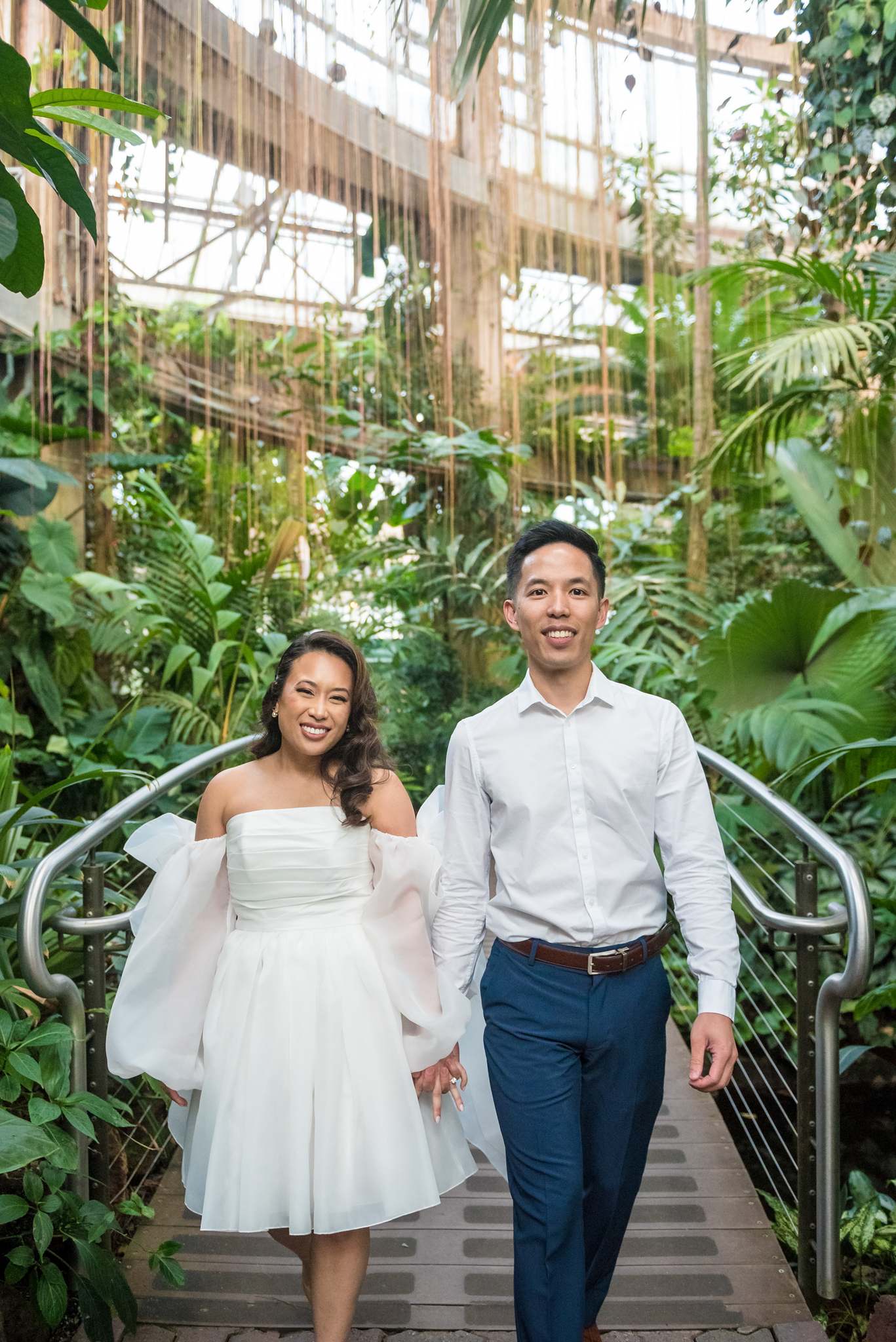 Vertical portrait of a laughing couple walking on the canopy walkway in the conservatory
