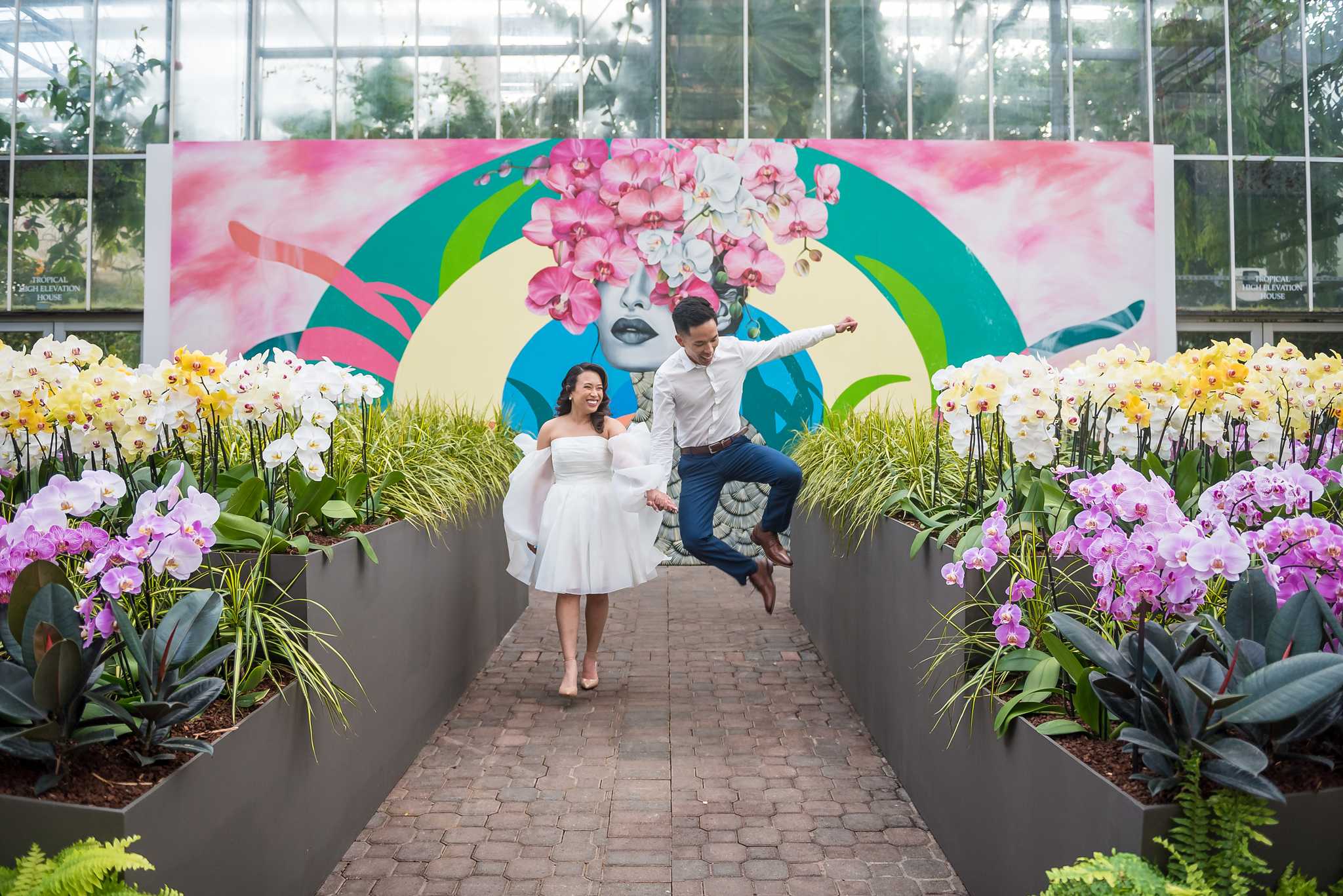 Playful jump in front of a bright orchid mural in the Fuqua Orchid Center