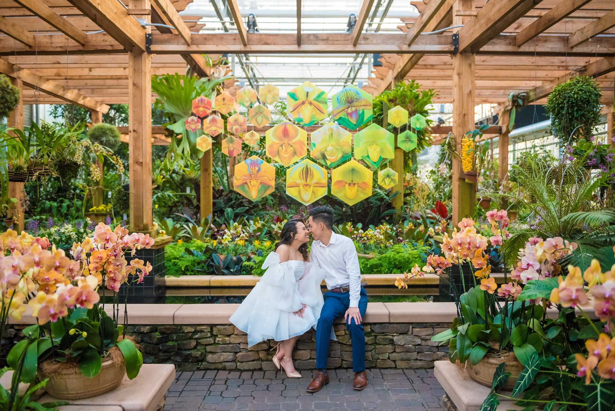 Couple seated on a bench beneath the orchid pergola in the Fuqua Orchid Center