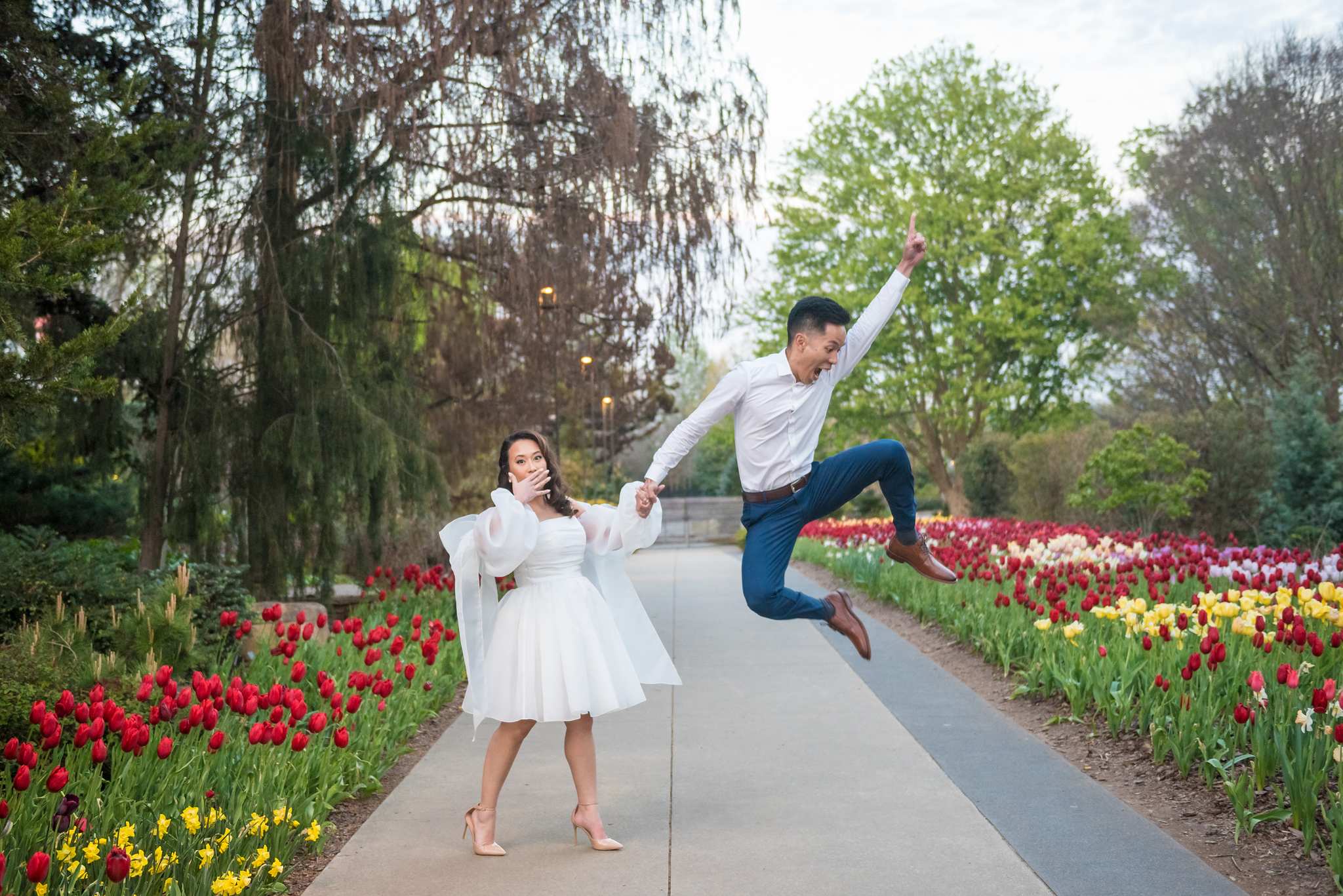 Partner leaping into the air beside a tulip-lined walkway at the Atlanta Botanical Garden