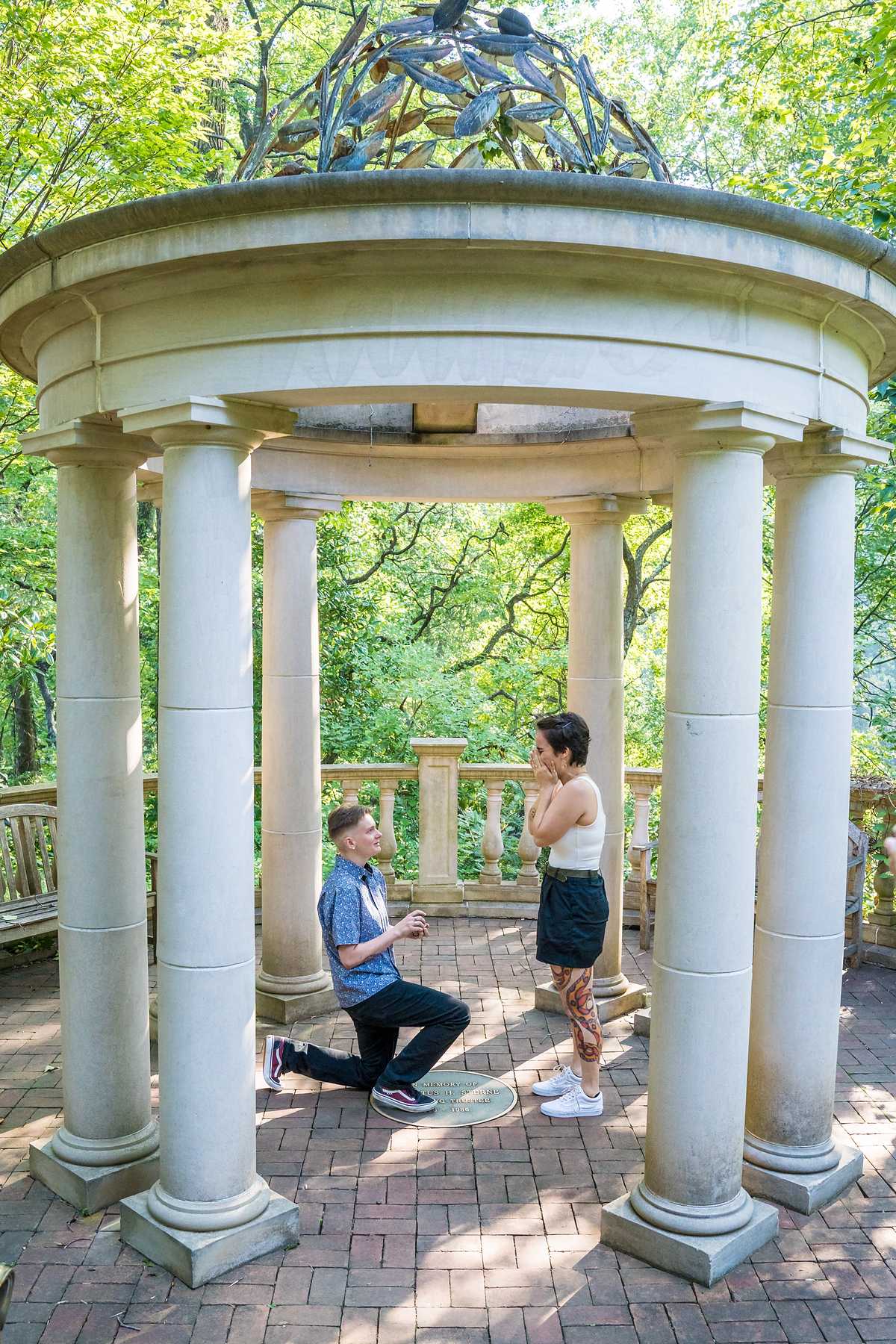 Wide view of a proposal on one knee framed by the columns of the Atlanta Botanical Garden gazebo