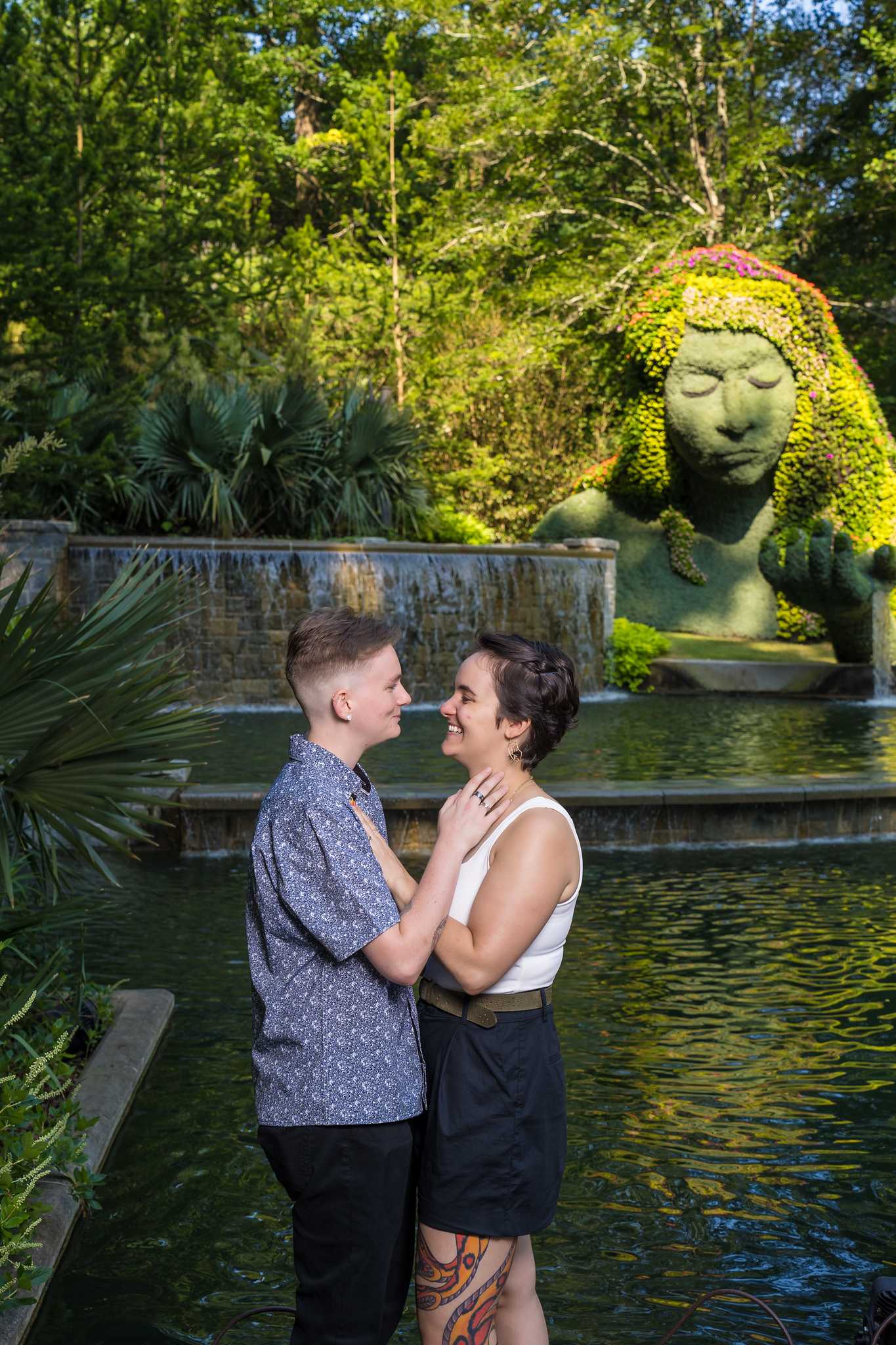 Engaged couple in front of the Earth Goddess plant sculpture and reflecting pool
