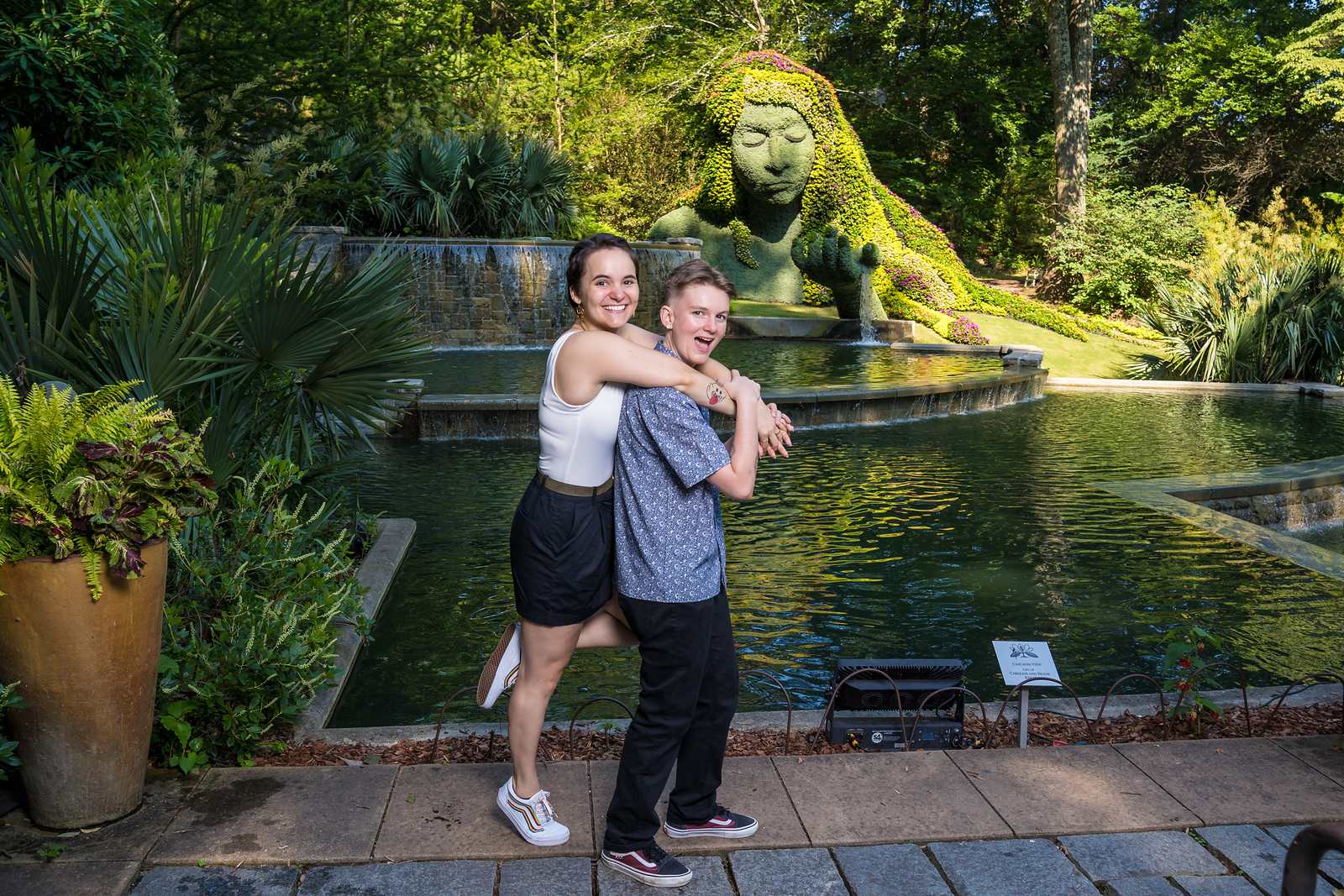 Engaged couple holding hands beside the Earth Goddess pool at the Atlanta Botanical Garden