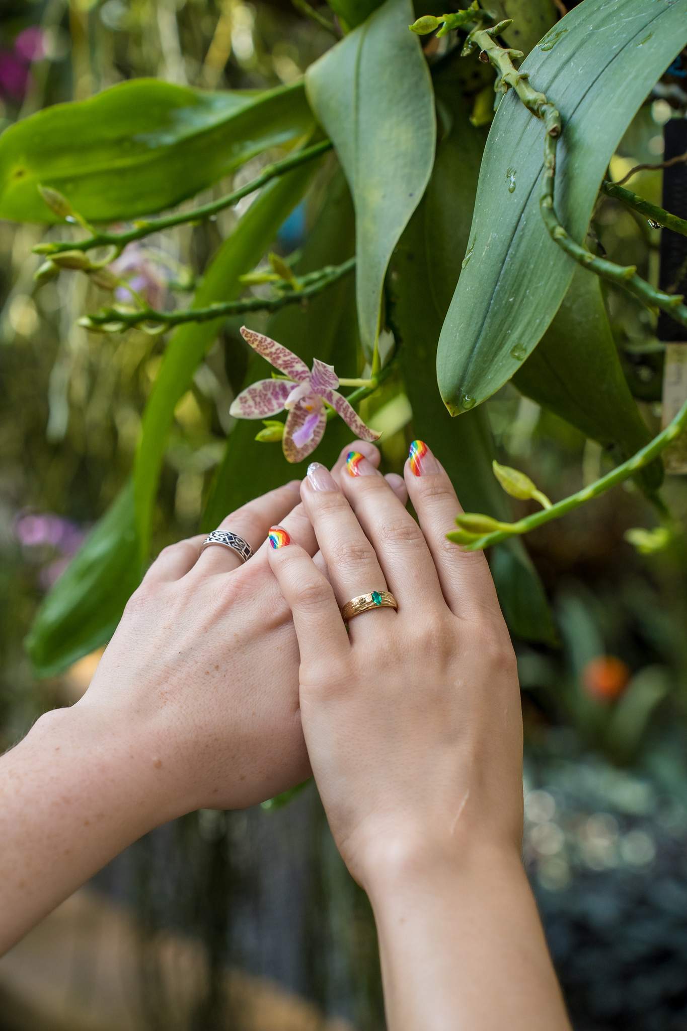 Hands showing an engagement ring beside a delicate orchid at the Atlanta Botanical Garden