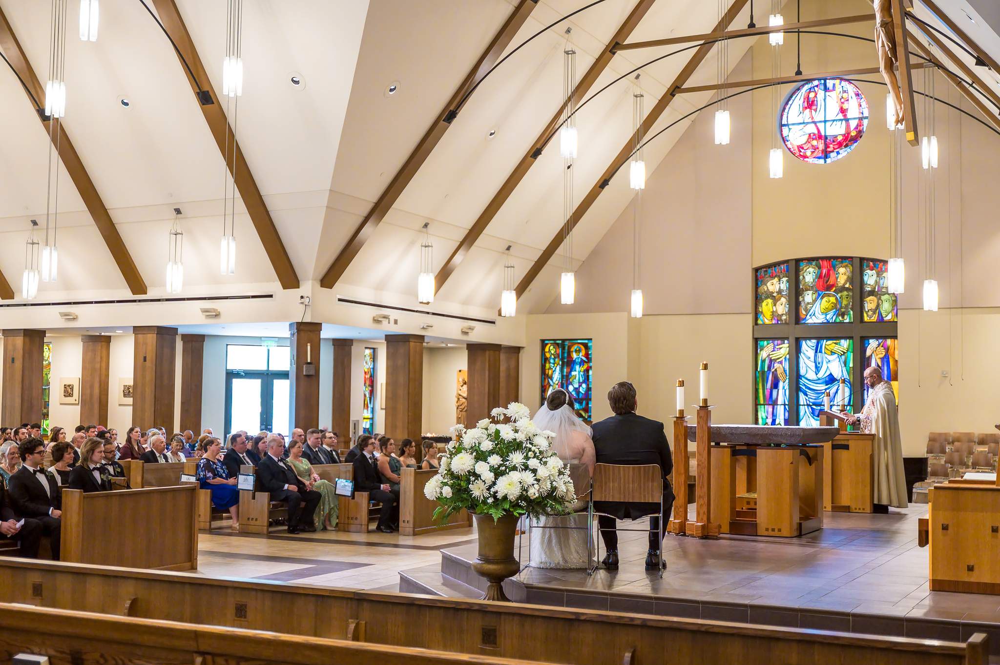 Wide view of a church wedding ceremony with stained glass and organ pipes