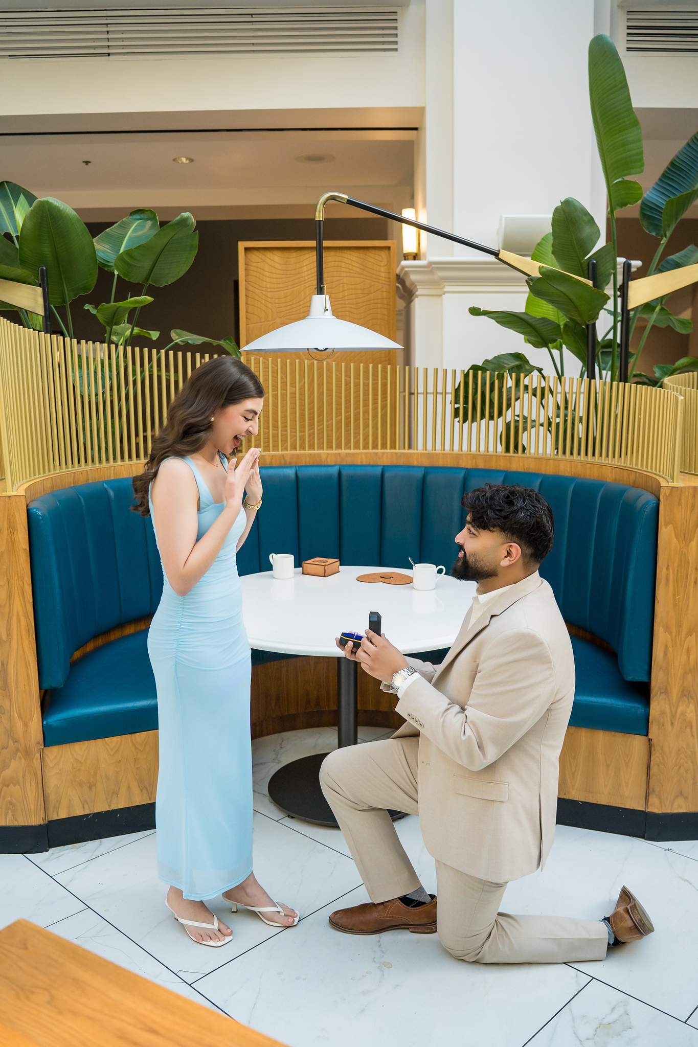 Man on one knee proposing beside the blue banquette lounge at Chateau Elan