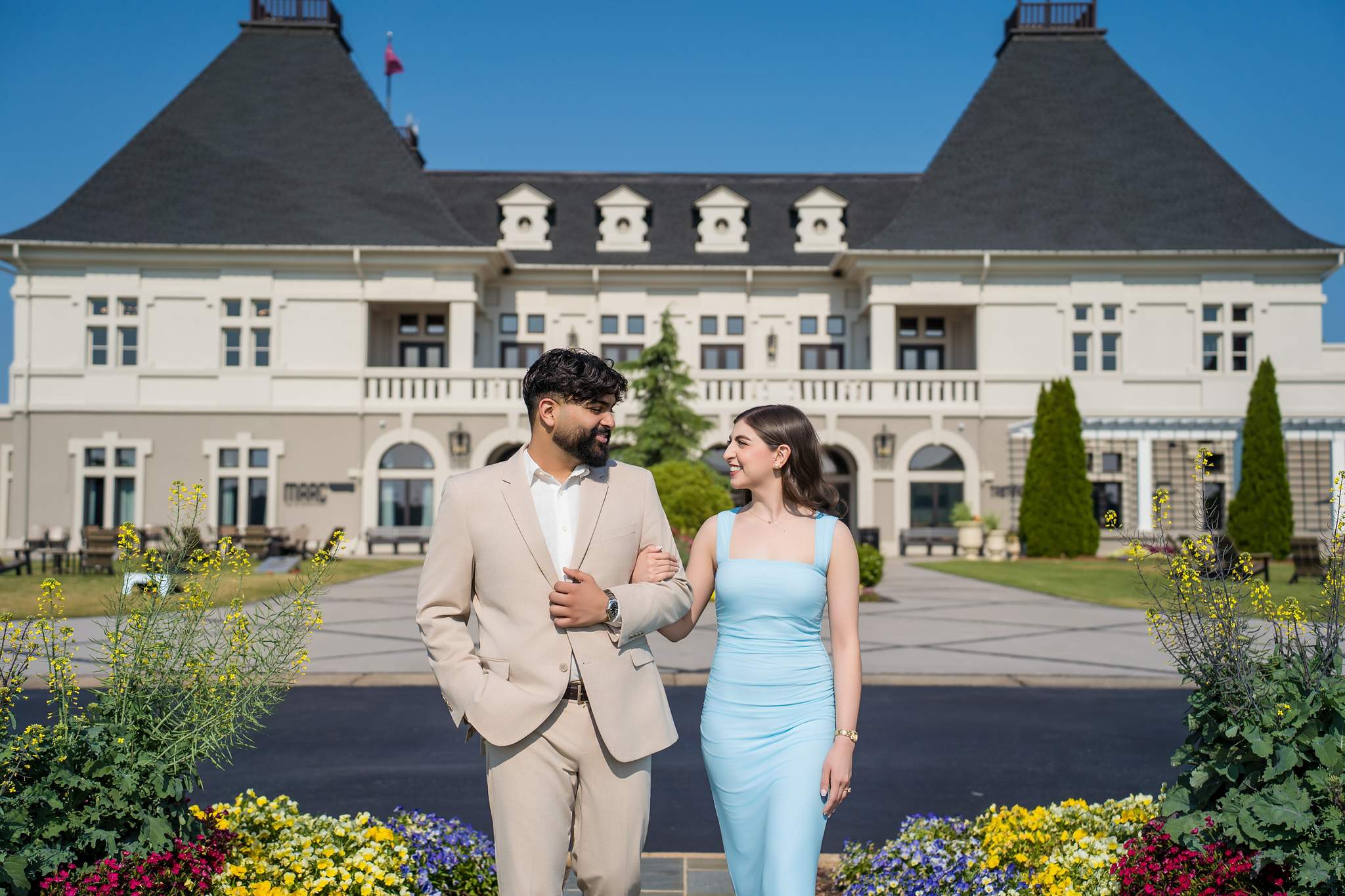 Engaged couple in front of the Chateau Elan chateau with colorful flower beds