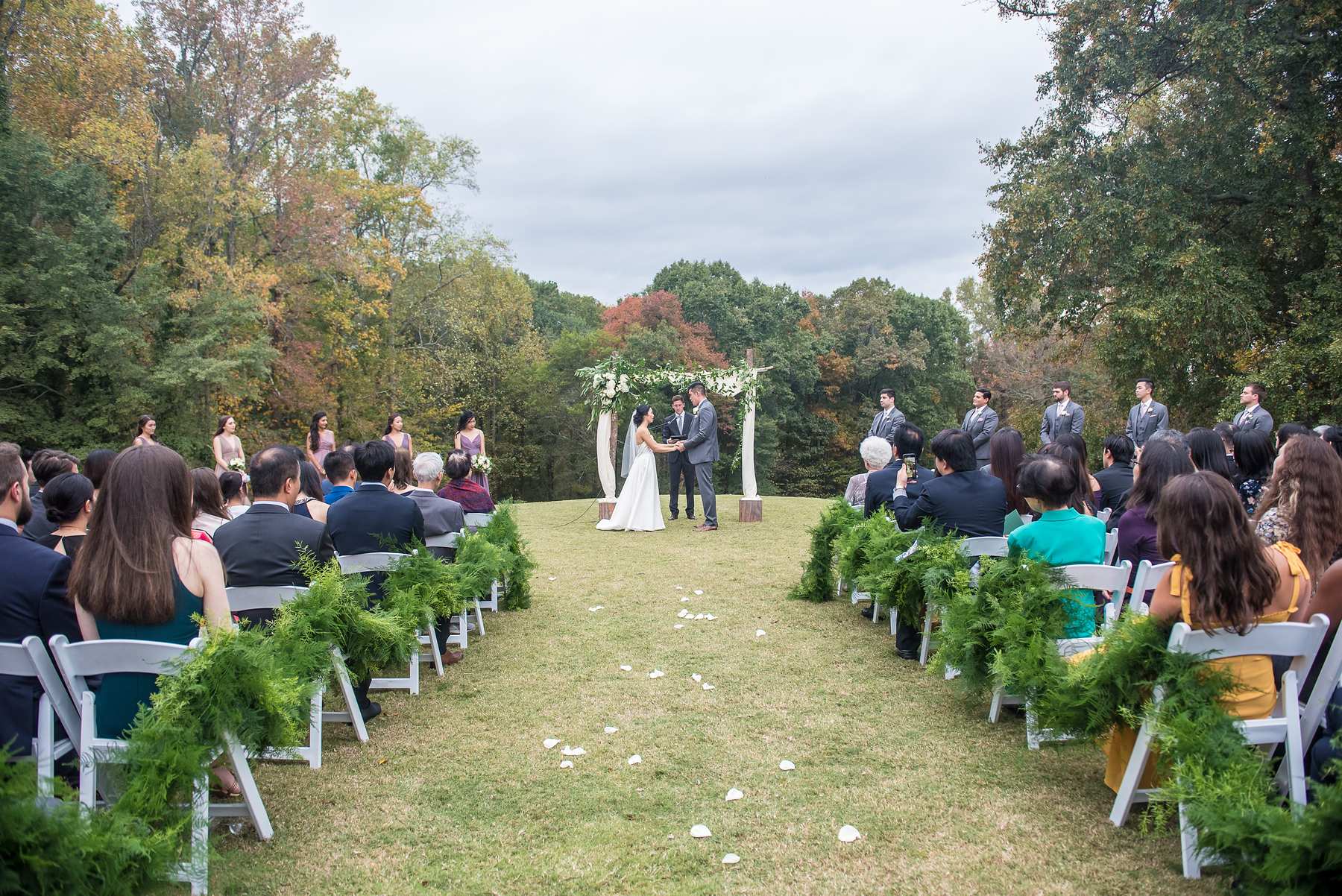 Guests watch the outdoor ceremony at Chateau Elan from the back of the tree-lined aisle