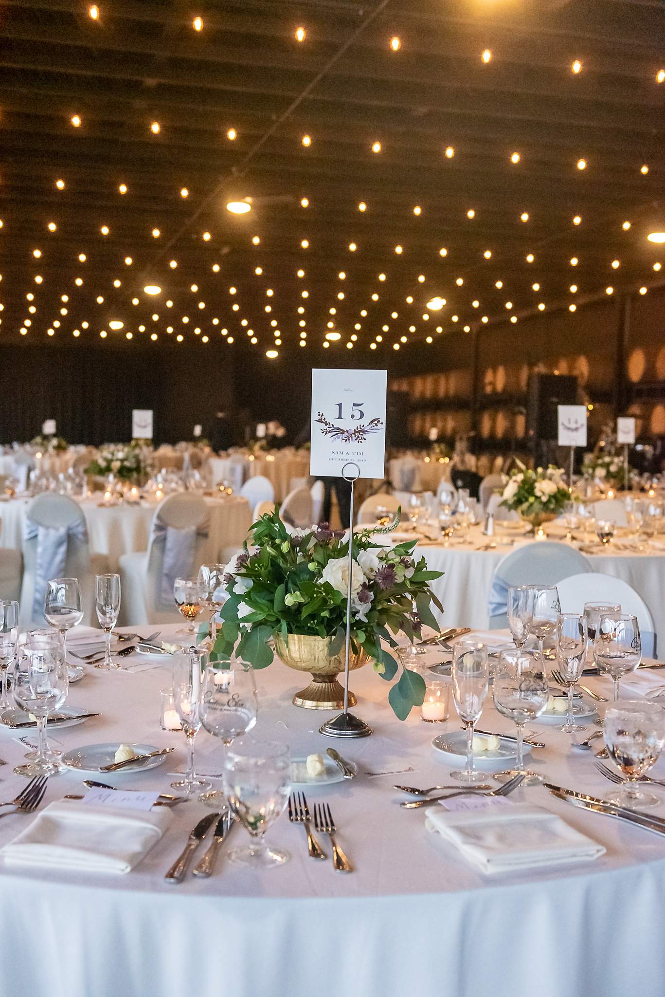 Round reception table with a greenery centerpiece under hundreds of string lights at Chateau Elan