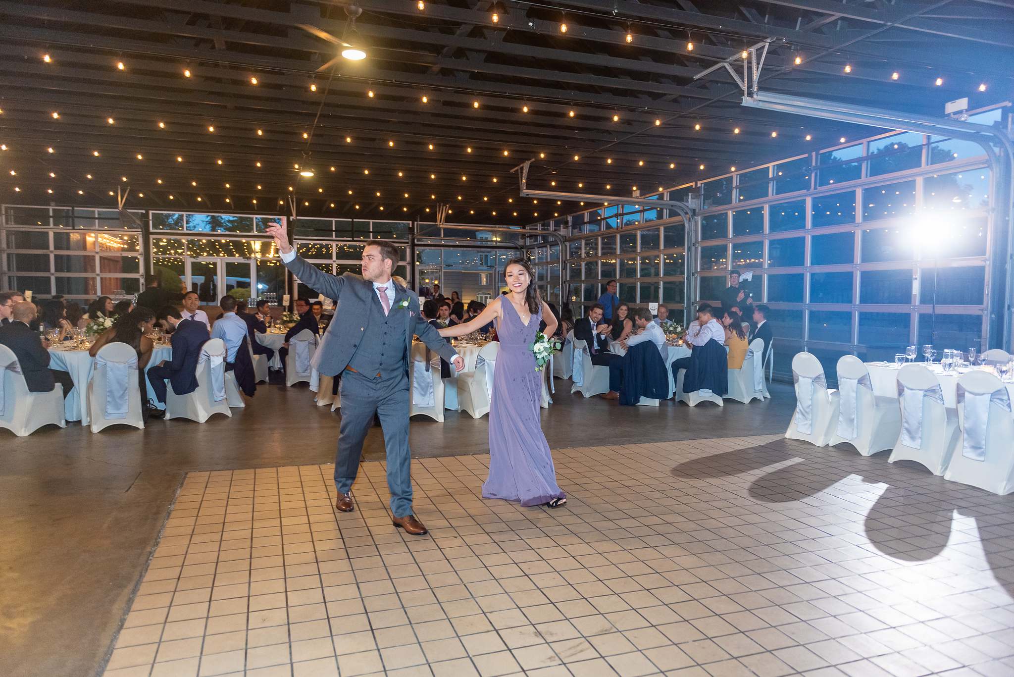 Wedding party members dance into the string-lit reception hall during the grand entrance