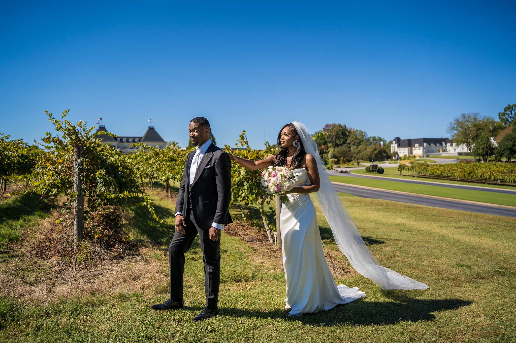 Bride reaches for the groom's shoulder during their first look in the Chateau Elan vineyard