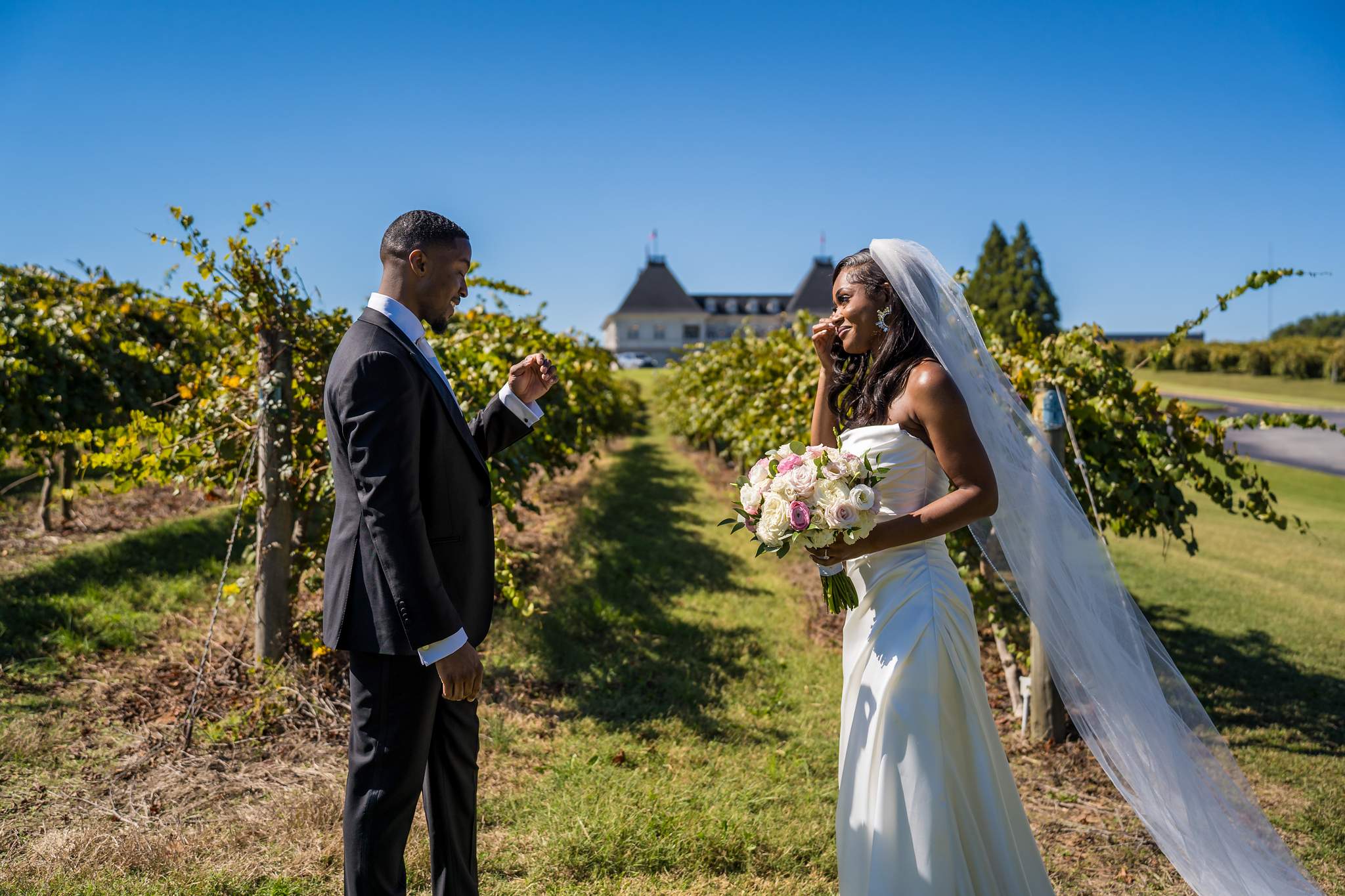 Groom turns to see the bride for the first time between the sunny vineyard rows