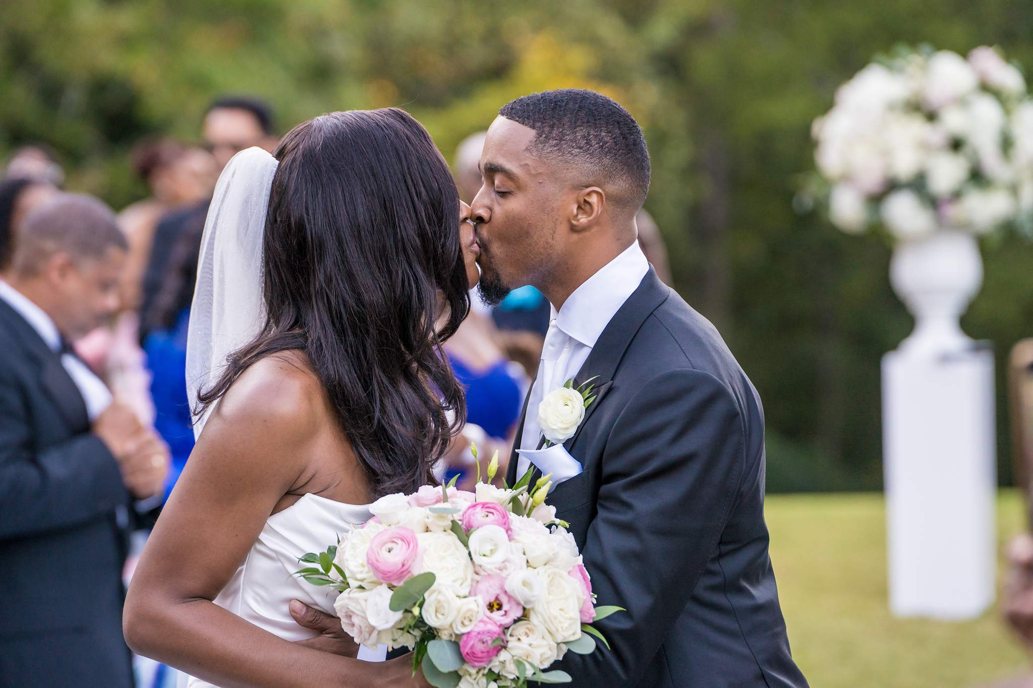 Close view of the bride and groom kissing as guests celebrate around them