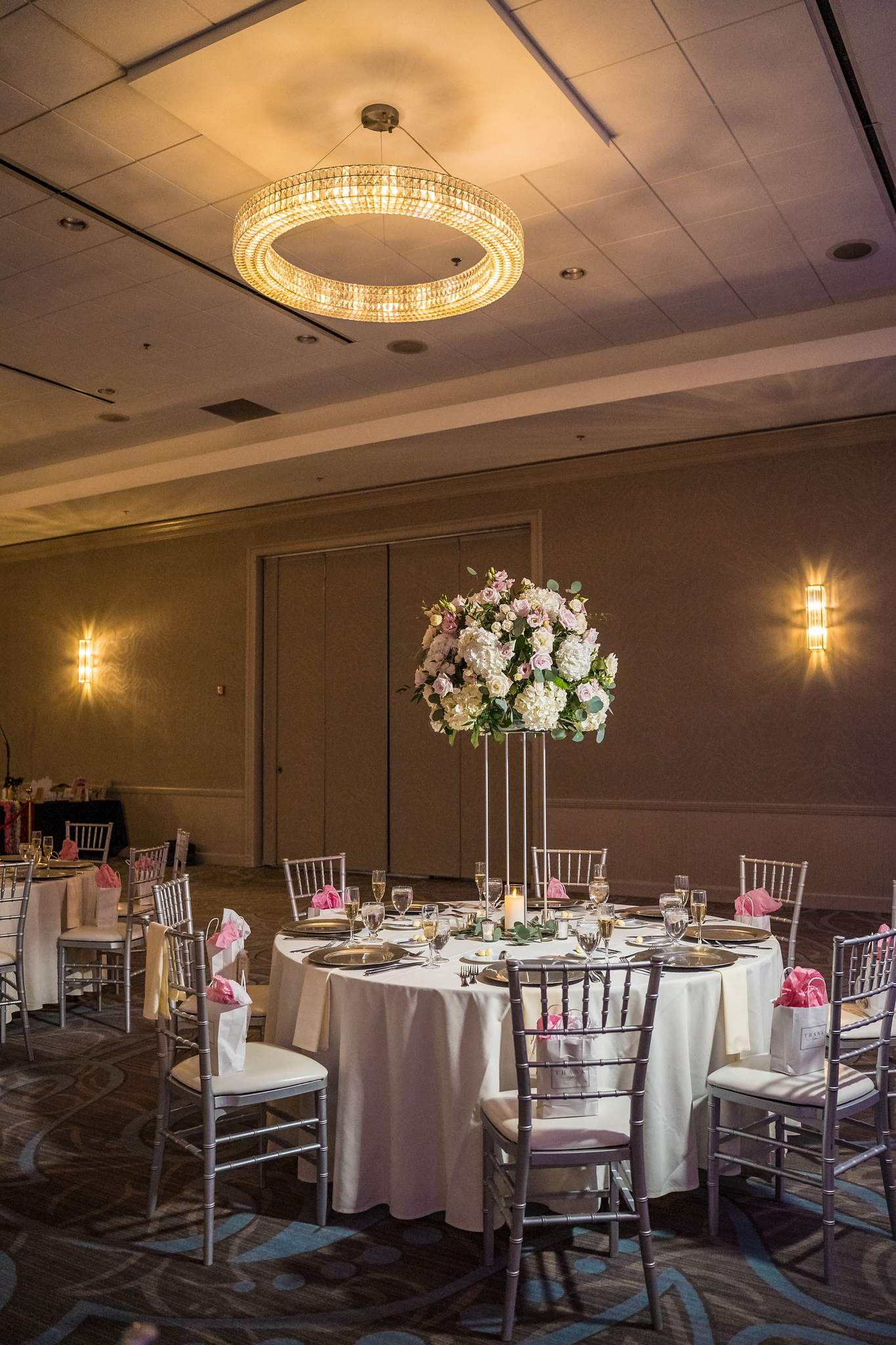 Ballroom reception set with tall floral centerpieces, chiavari chairs and soft wall sconces at Chateau Elan