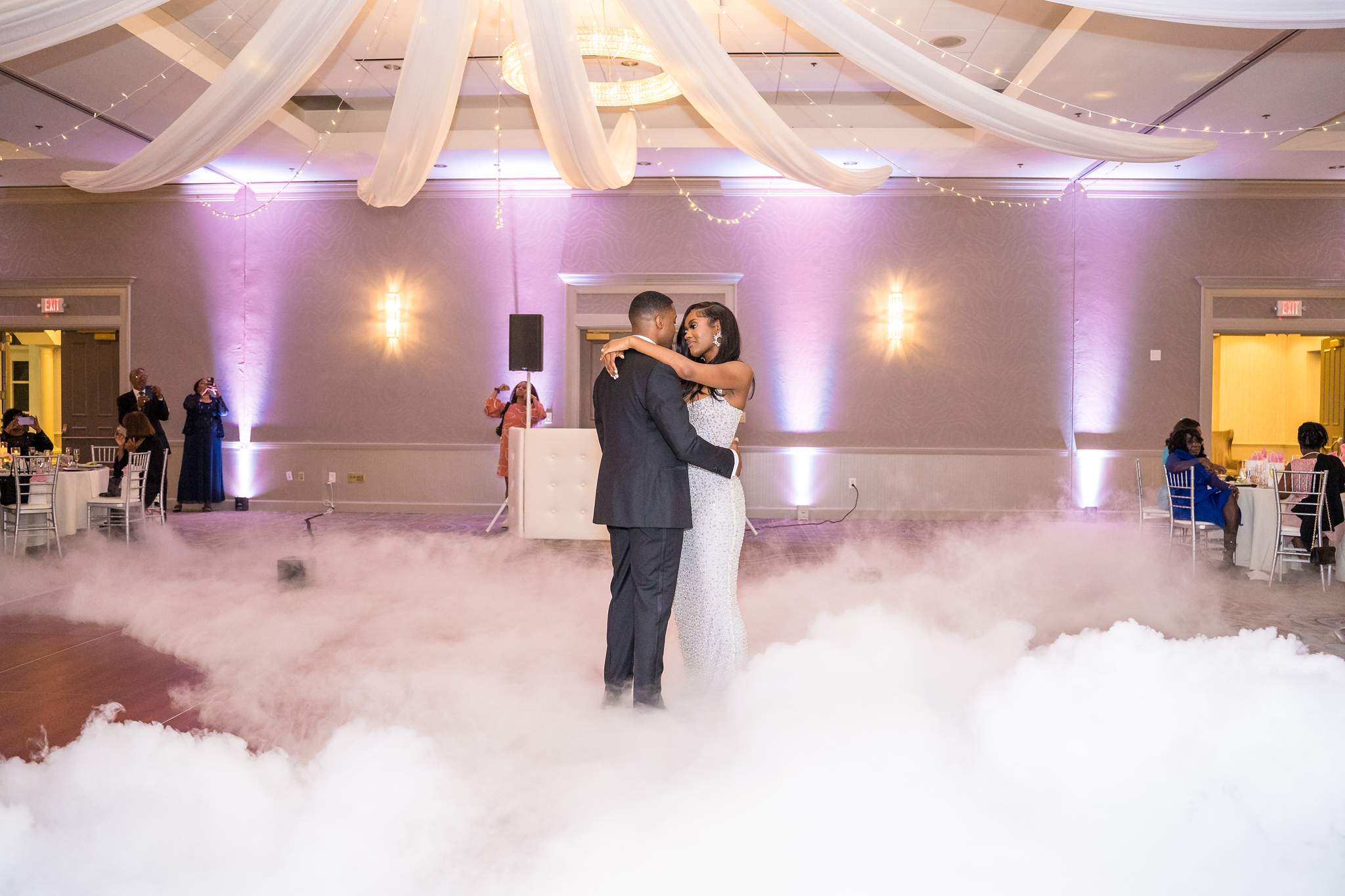 Bride and groom embrace in a sea of low fog during their first dance
