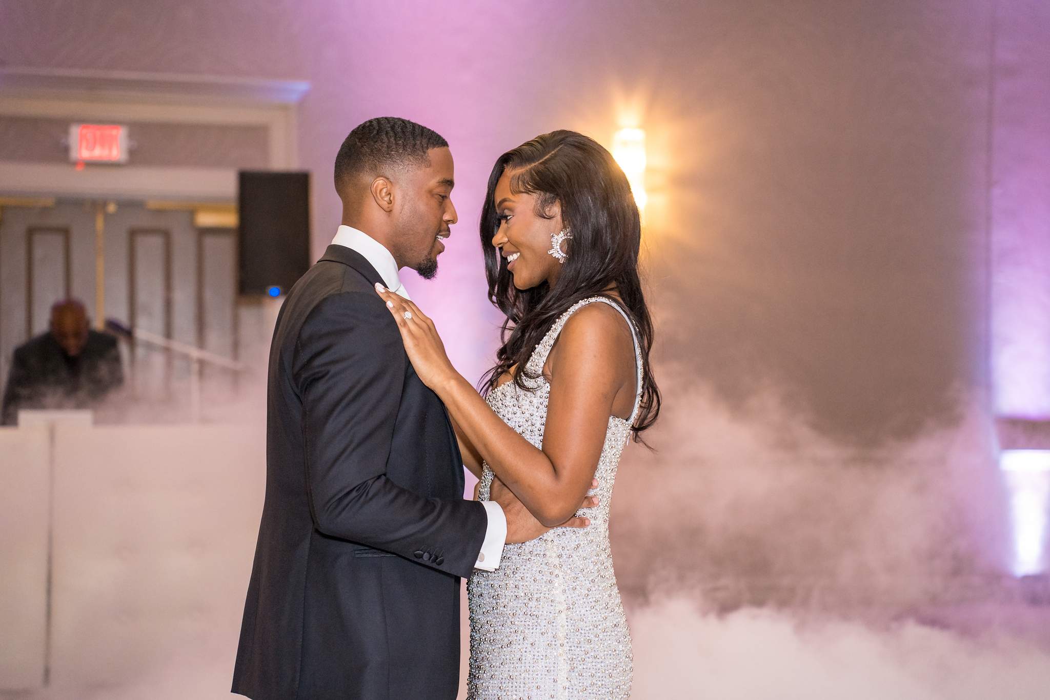 Groom and bride gaze at each other during their first dance under soft purple light