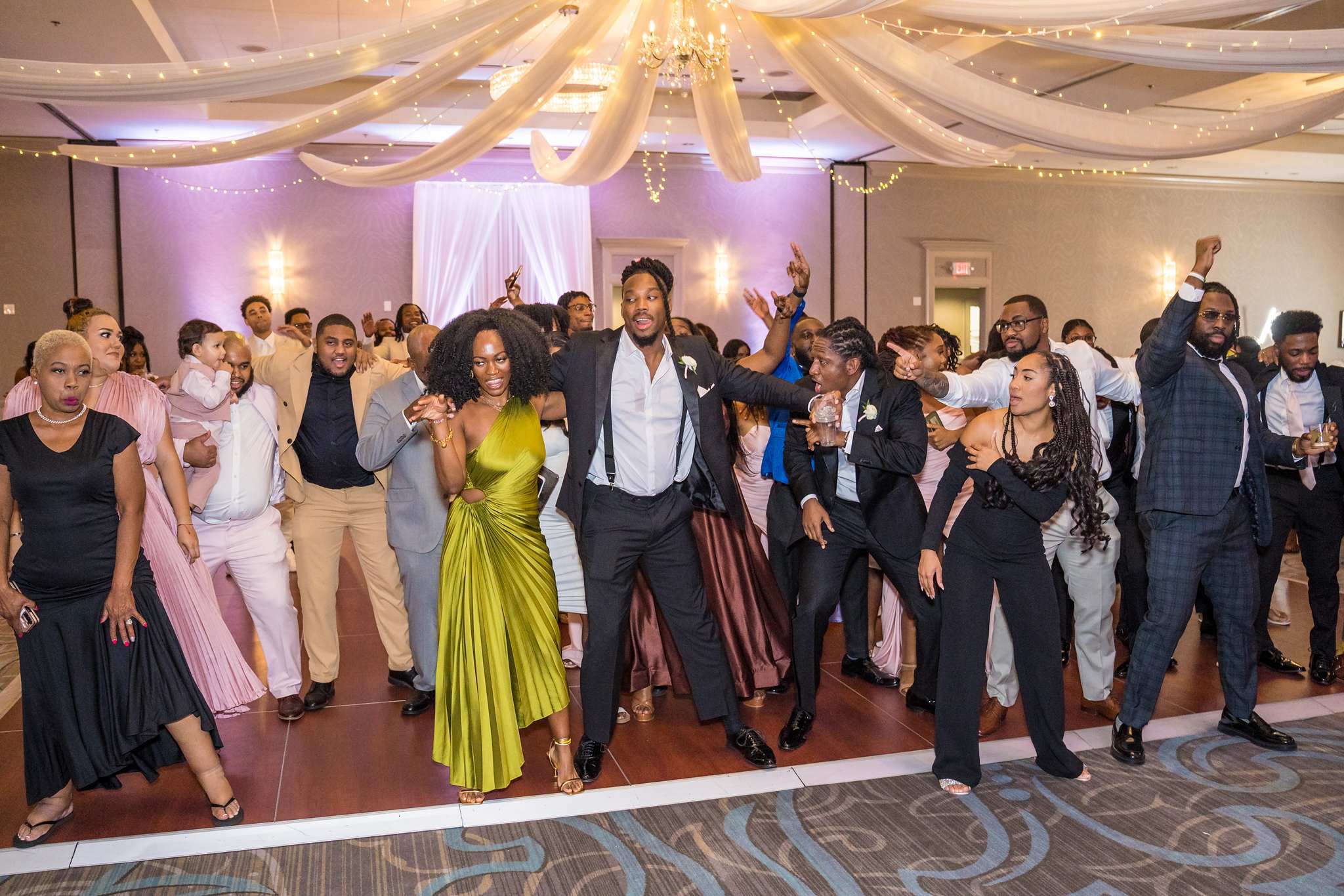 Guests fill the dance floor with arms raised during the reception at Chateau Elan