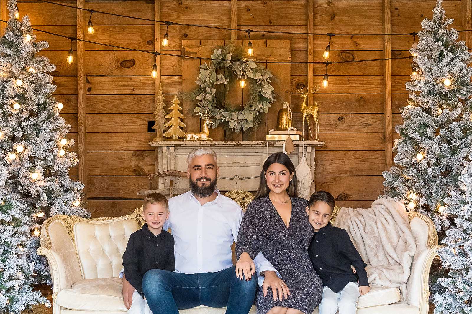 Family of four in black, white and charcoal on the white settee in the Christmas Barn at Prospect Farms
