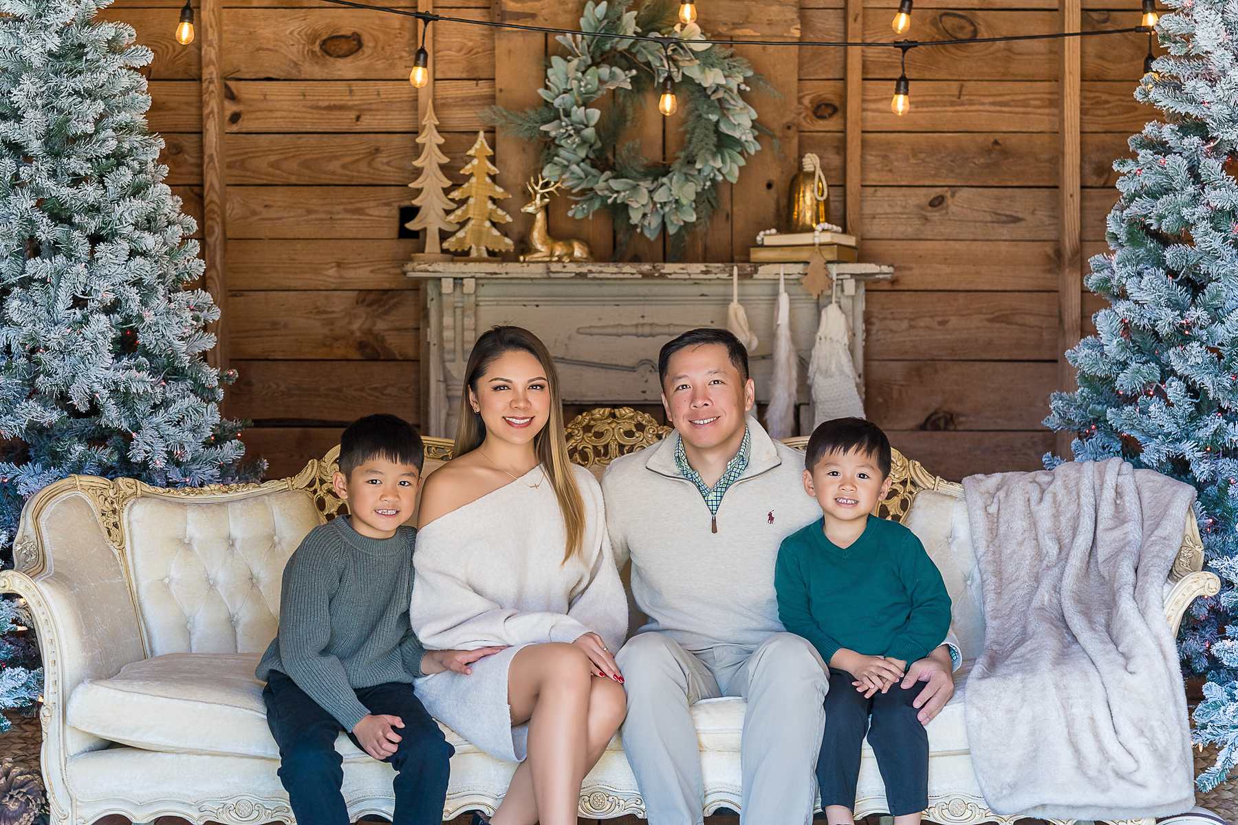 Family in cream, gray and emerald on the white settee in the Christmas Barn at Prospect Farms