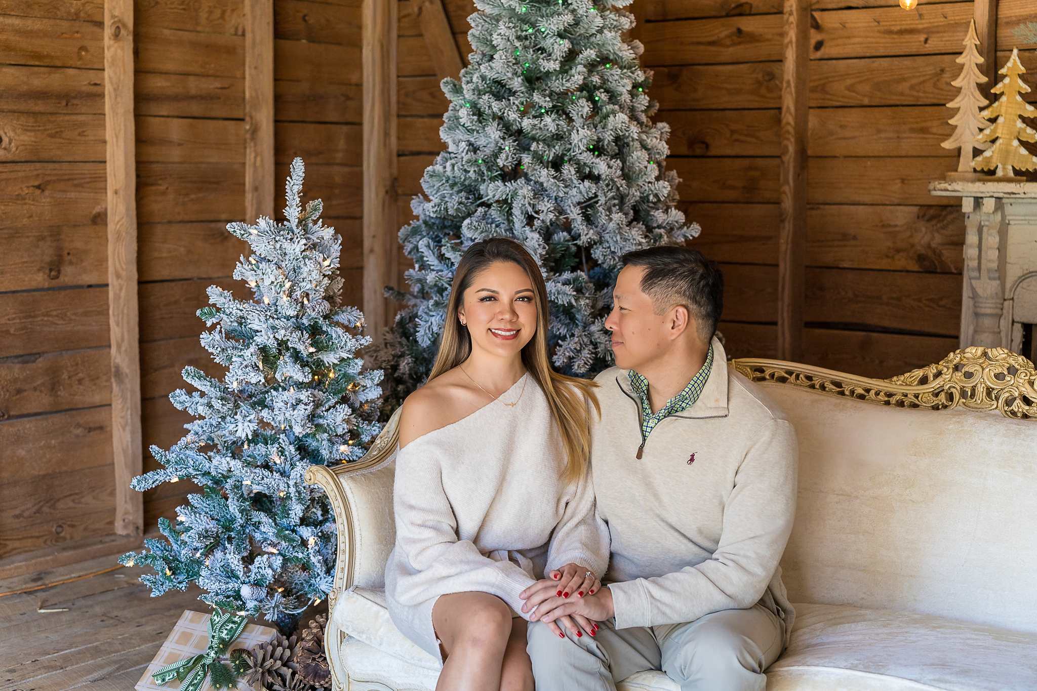 Couple in coordinating cream neutrals on the tufted settee in the Christmas Barn