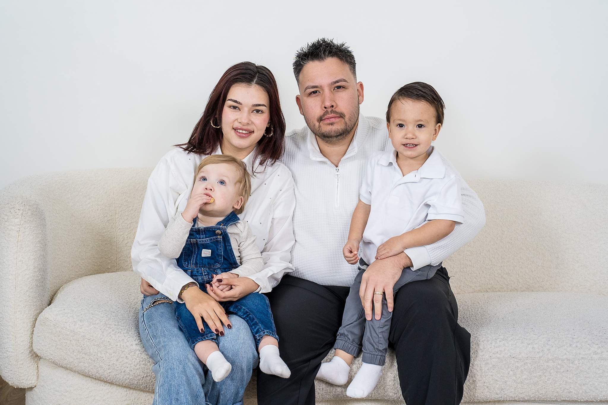 Family in white shirts and denim on a white sofa