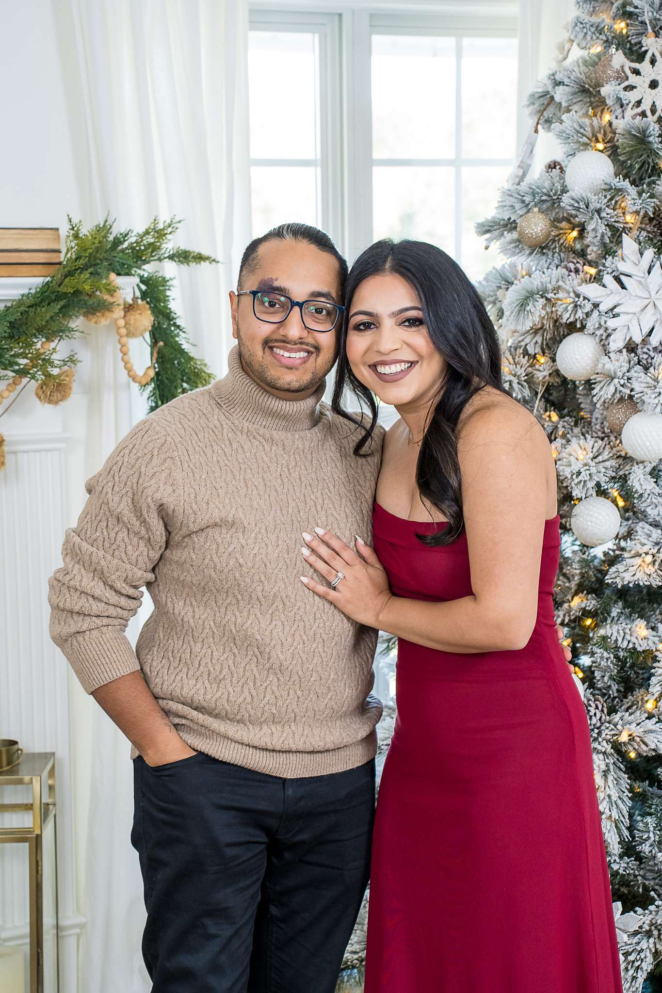 Couple in burgundy and camel posing beside a Christmas tree