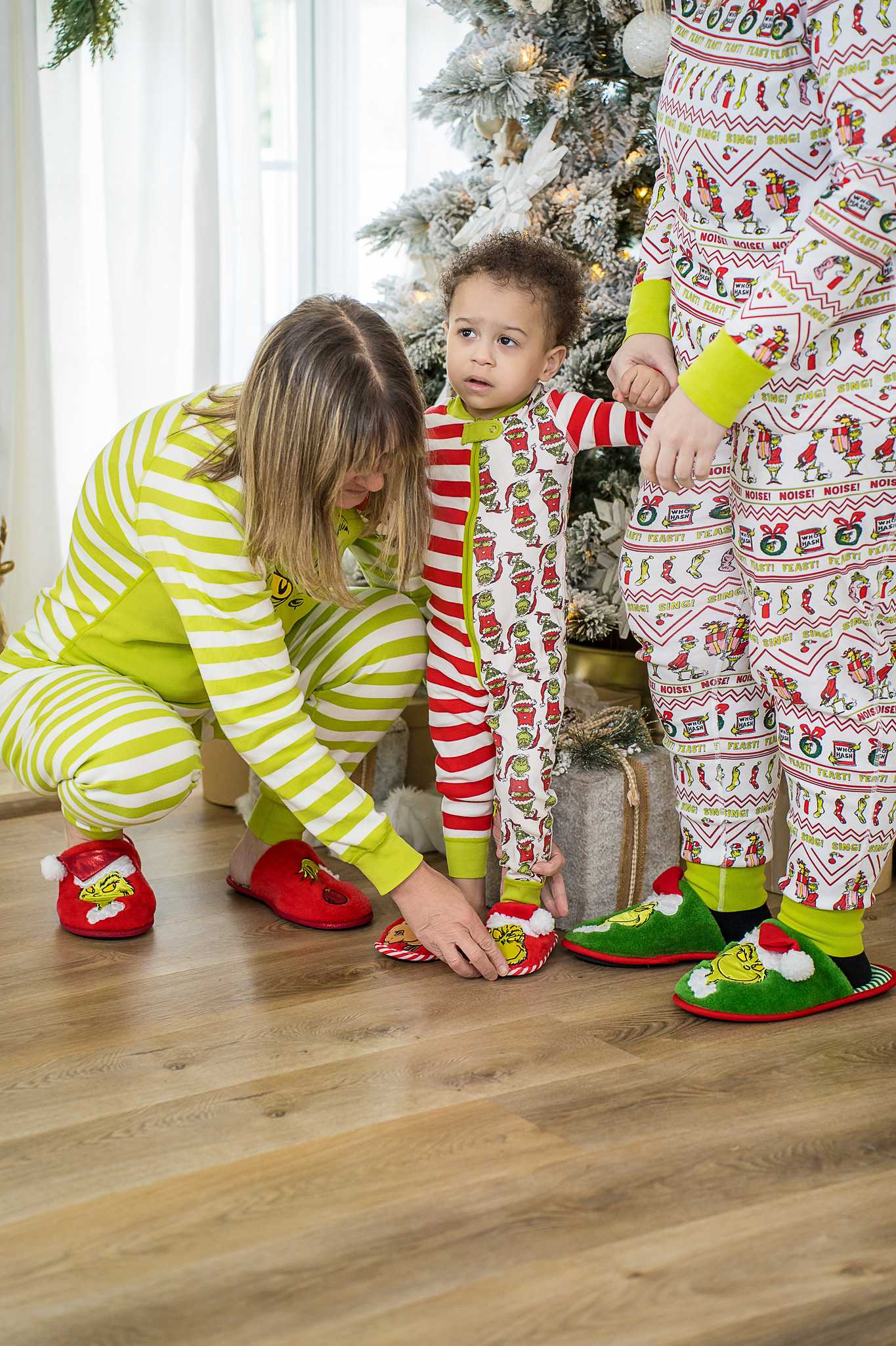 Family in matching holiday pajamas beside the Christmas tree