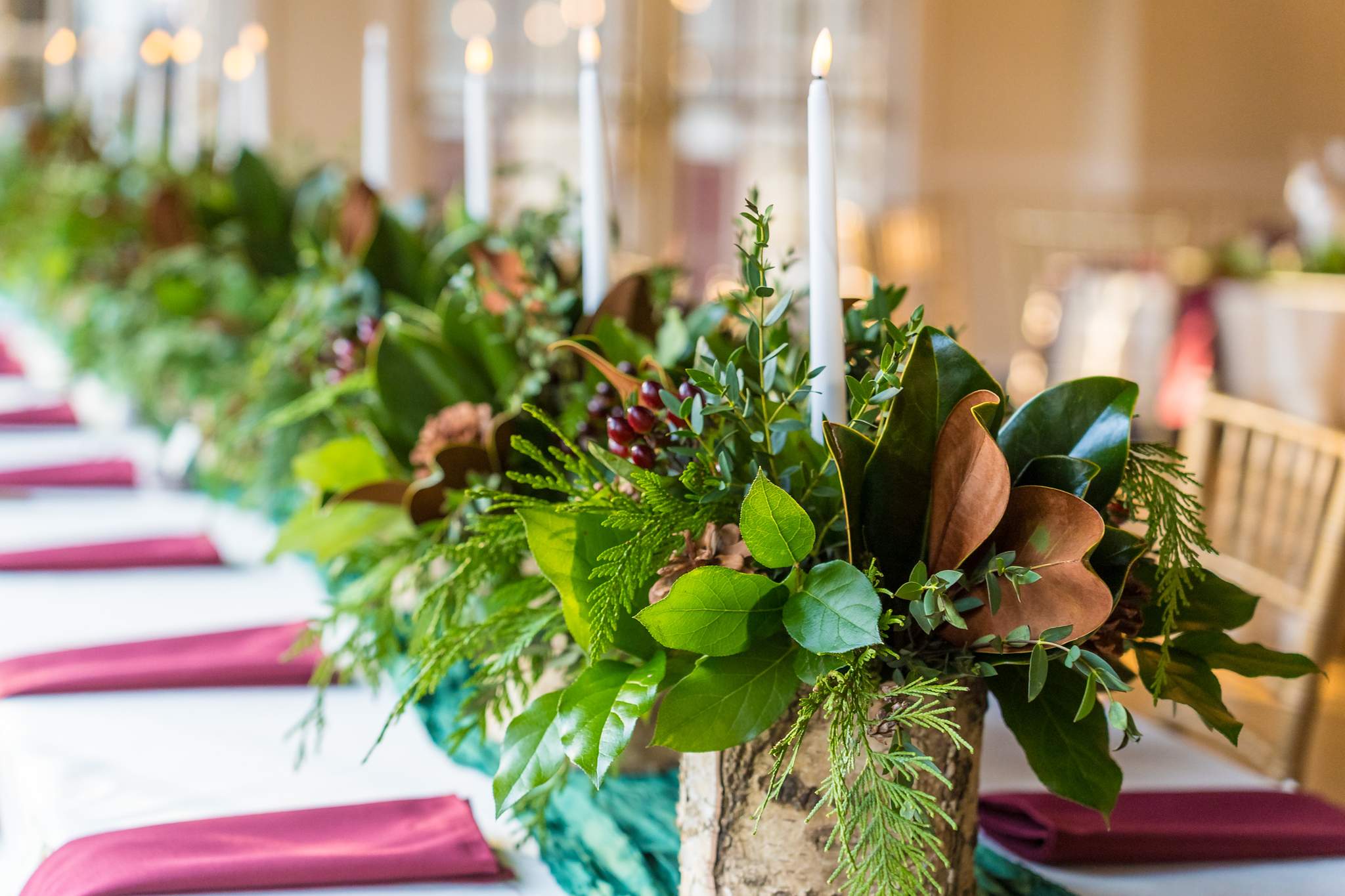Magnolia and greenery garland with candles on a Christmas wedding head table