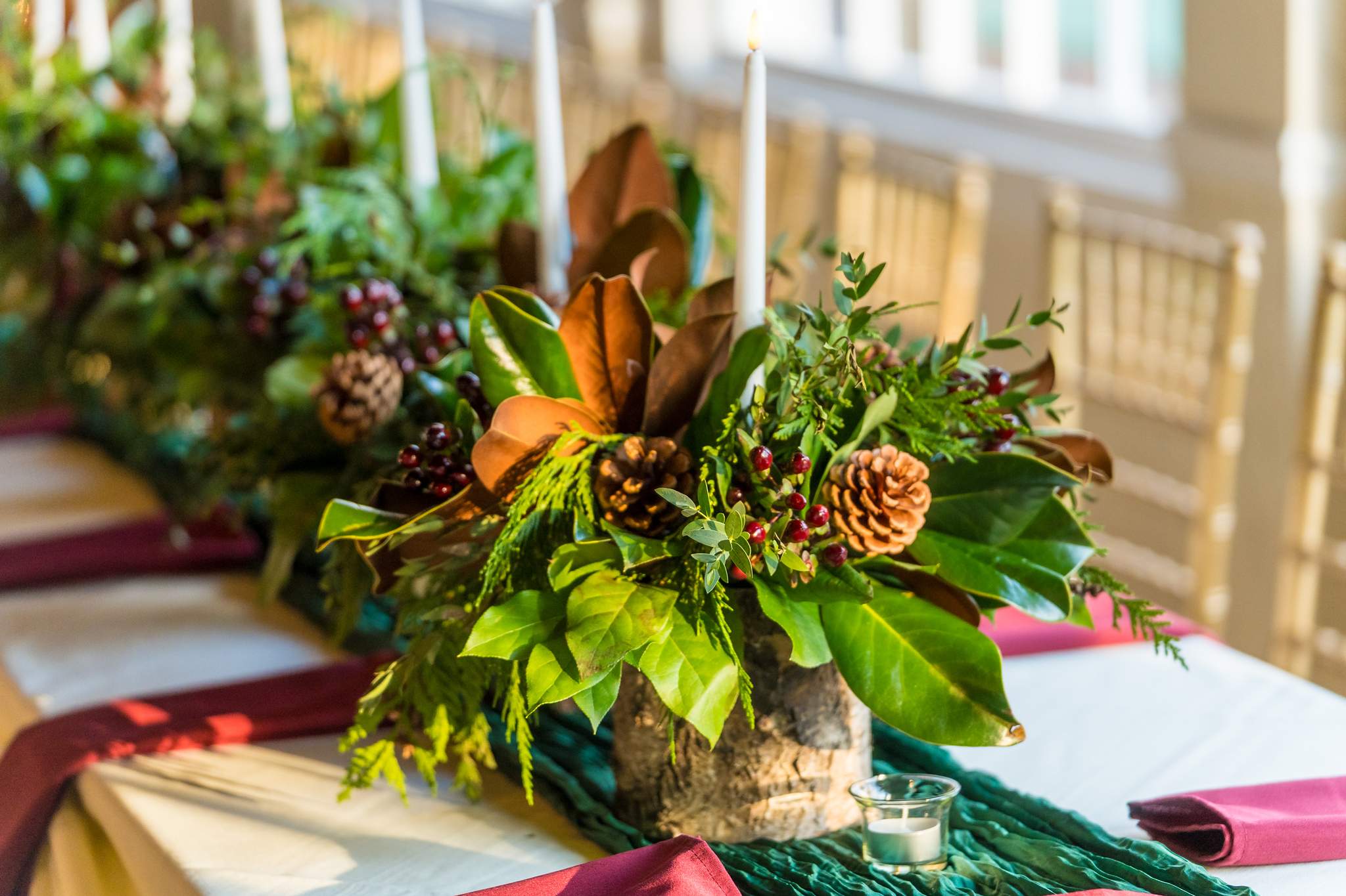 Close up of a magnolia, pinecone and greenery centerpiece for a Christmas wedding