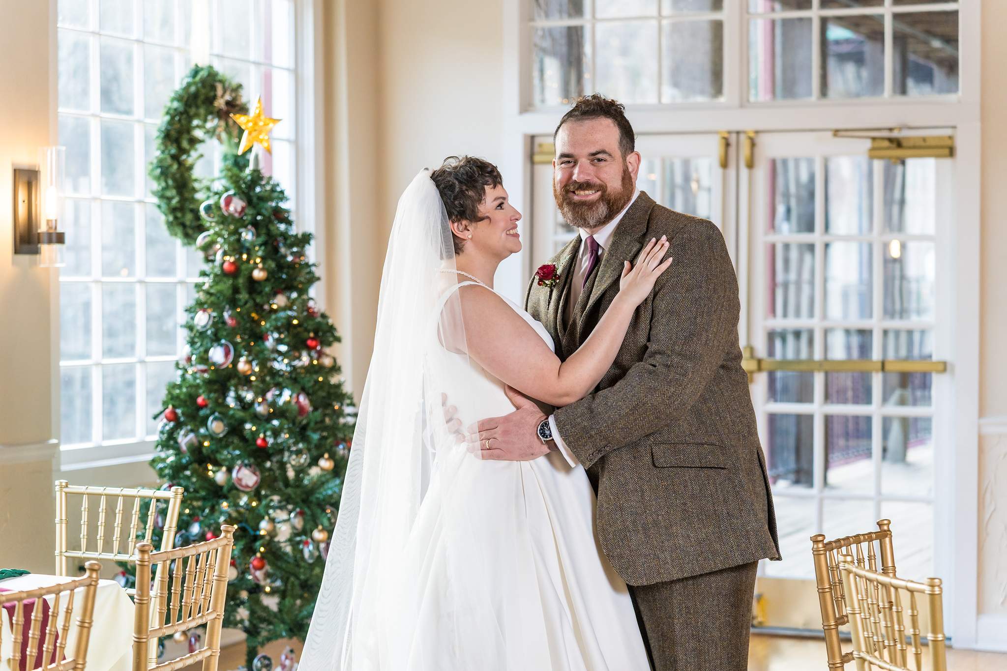 Couple embracing beside a Christmas tree at their December wedding in Atlanta