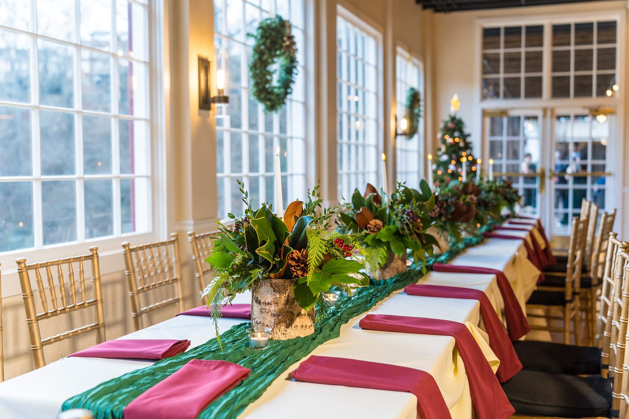 Head table with greenery garland and wreaths in the windows at a Christmas wedding