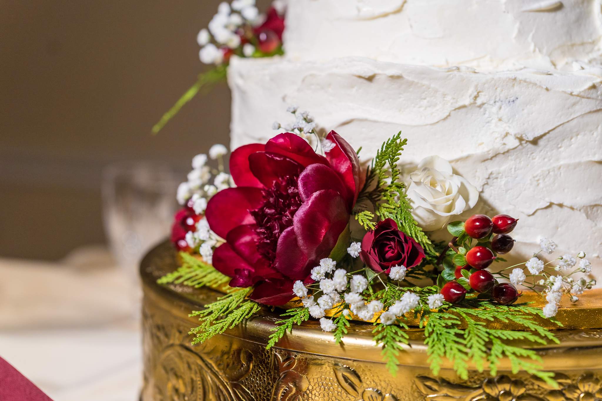 Christmas wedding cake decorated with red flowers, berries and cedar