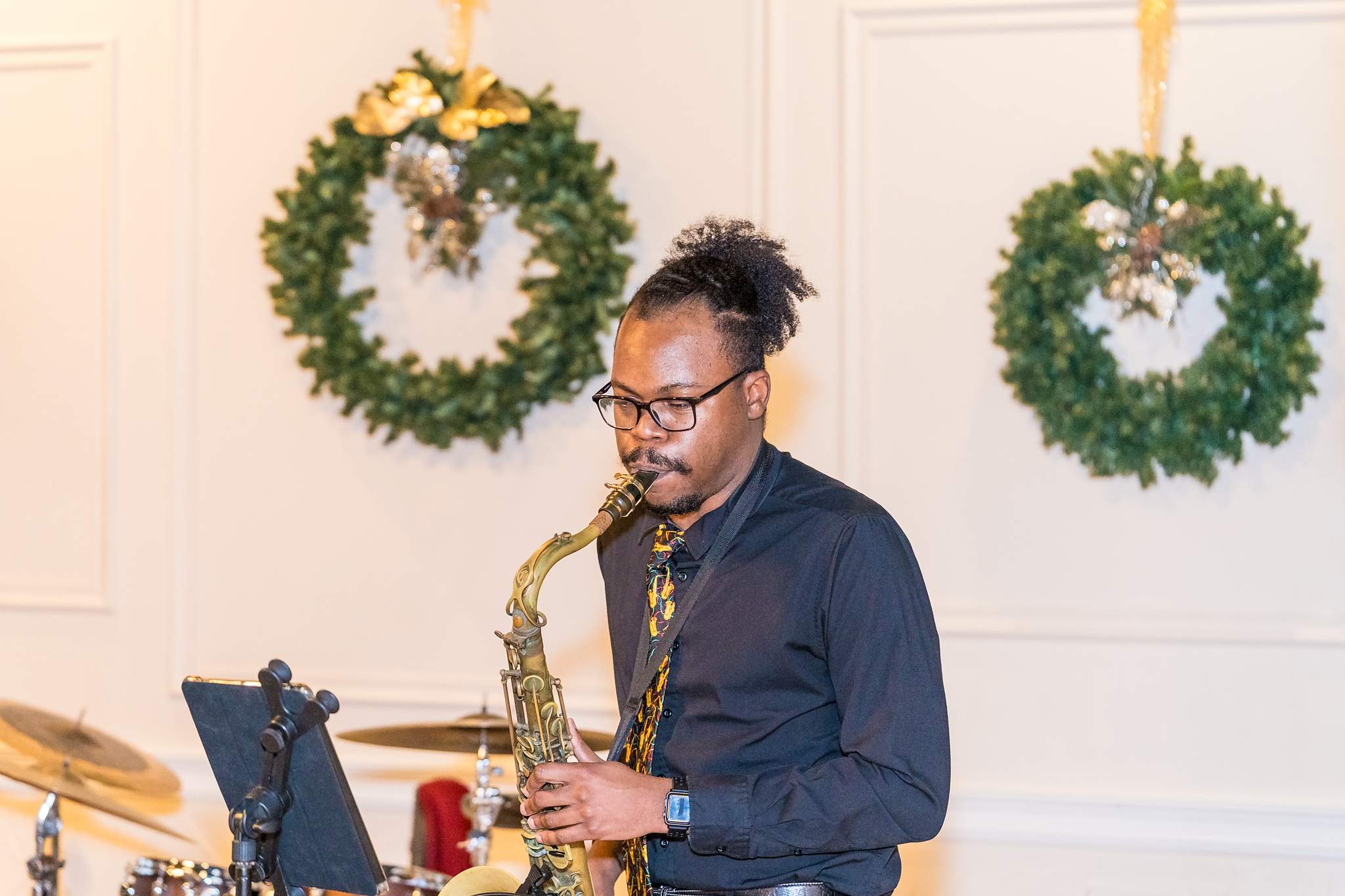 Saxophonist playing in front of Christmas wreaths at a wedding reception