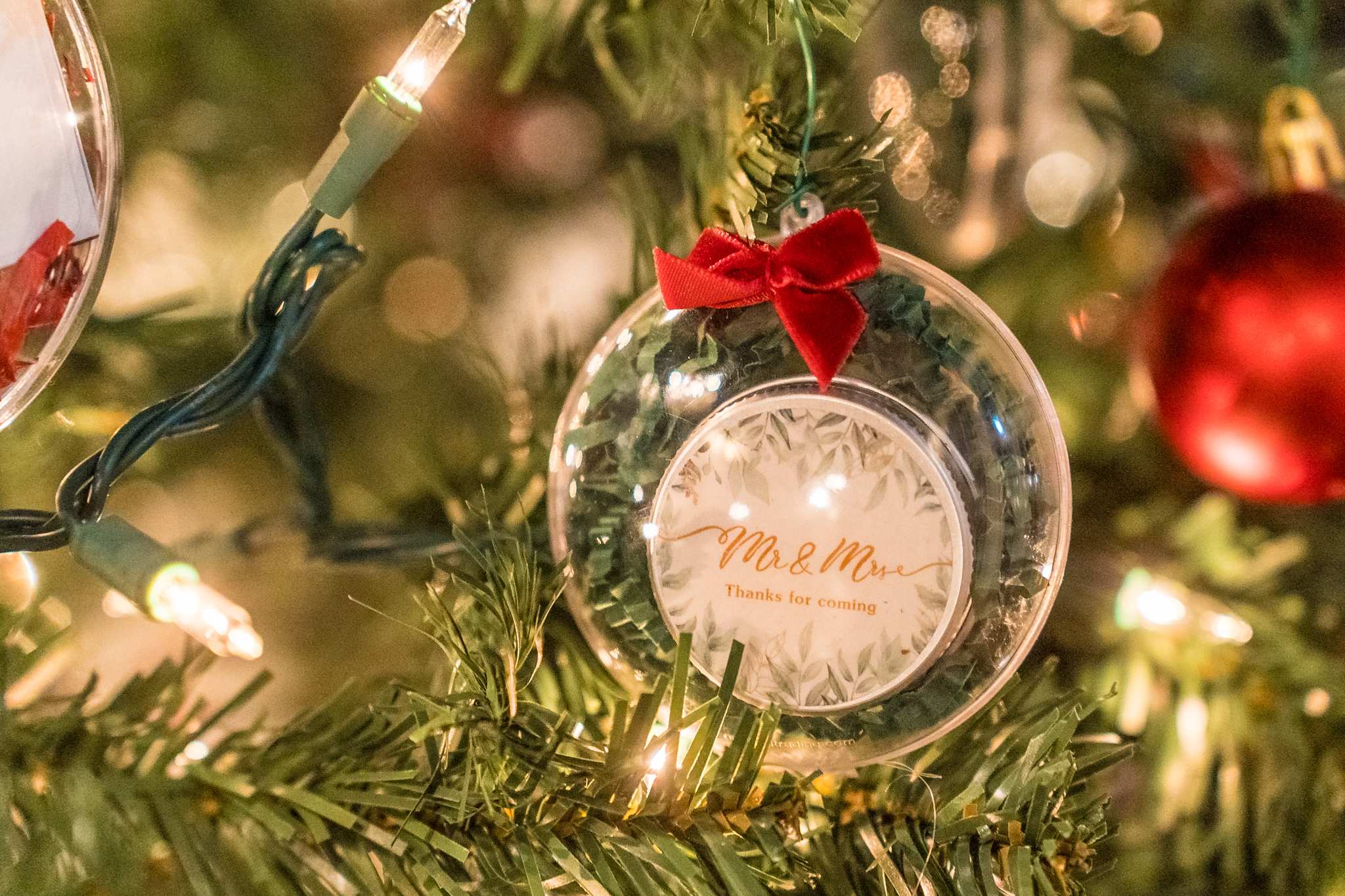 Personalized ornament hanging on a Christmas tree at a wedding